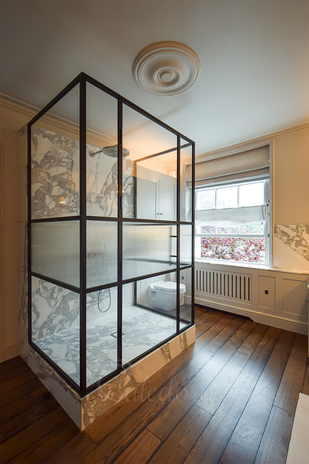 Black charcoal powder coated three-sided shower enclosure with reeded glass middle panel and marble walls