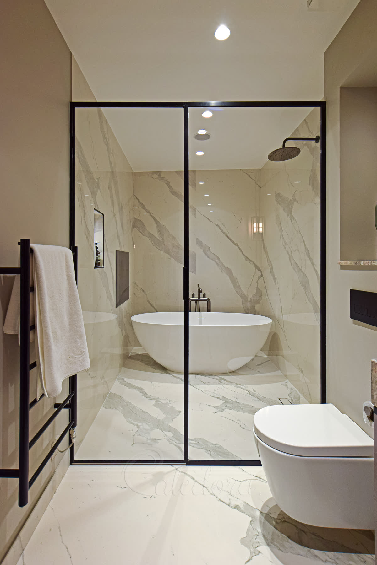 Black framed inline shower enclosure as a bathroom partition with marble walls