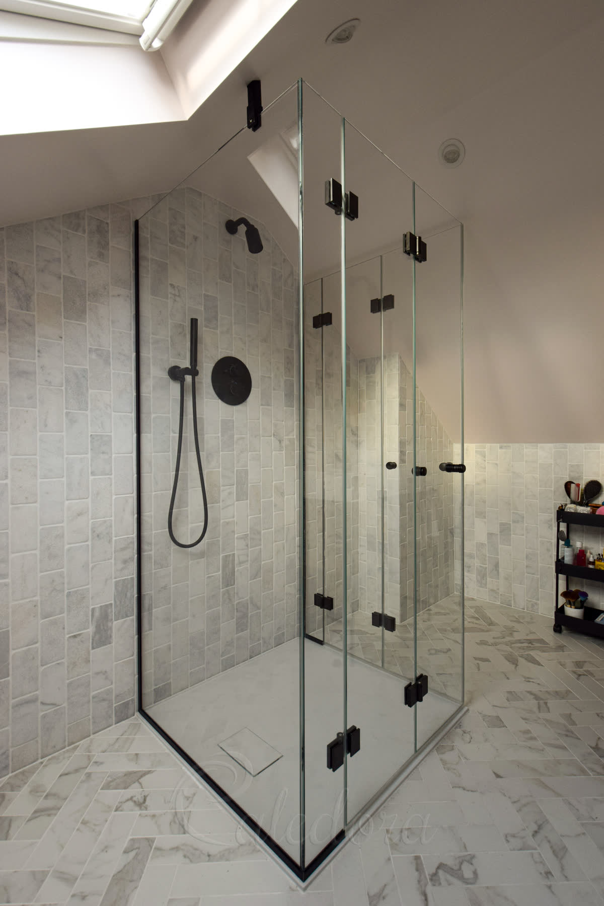 Black frameless three-sided shower with bifold doors showing prominent black hardware for navigation reference