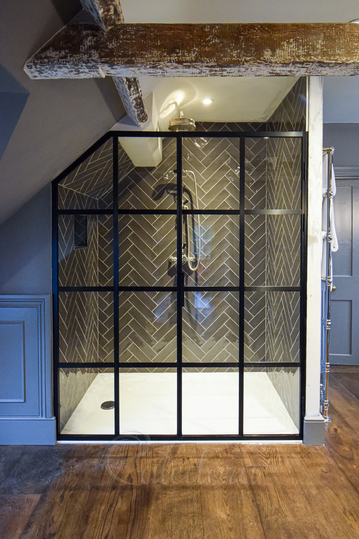 Black grid alcove shower door with an inline panel and dark herringbone tiles