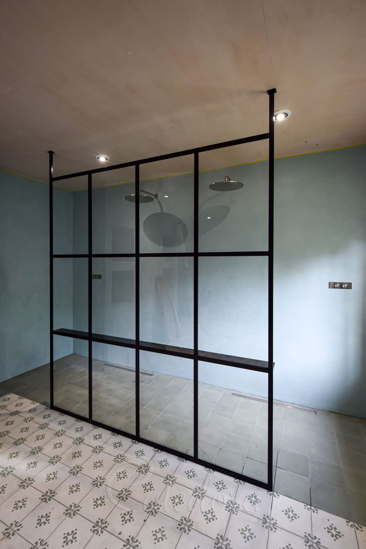 Large black grid full height shower screen with sage green walls and patterned floor tiles