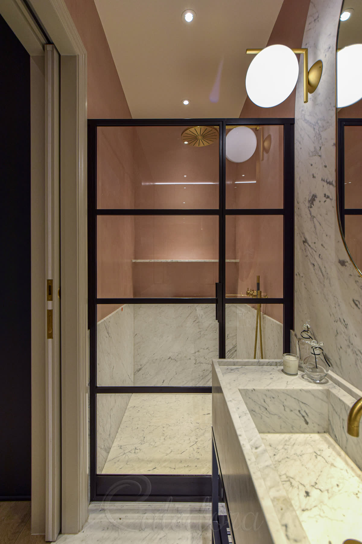 Deep black industrial grid shower door with inline panel and pink microcement wall finish