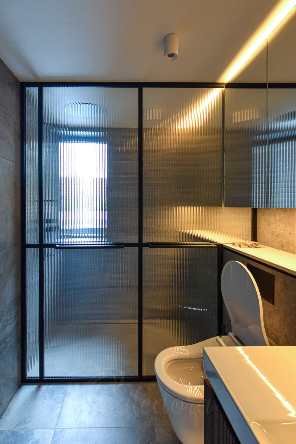 Black shower enclosure with reeded glass panels in a compact modern bathroom