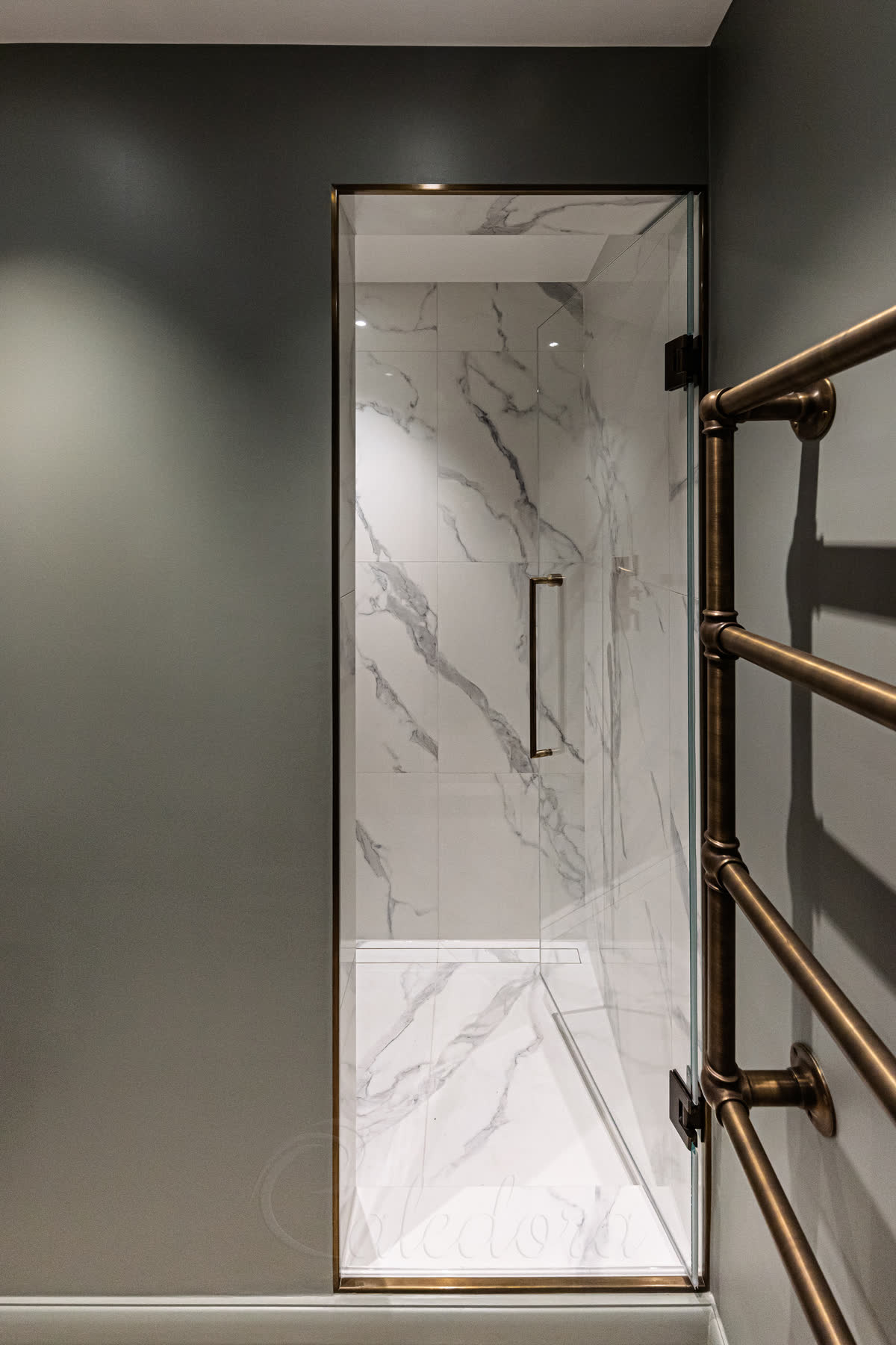 Antique brass shower door with matching antique brass towel radiator on the bathroom wall outside