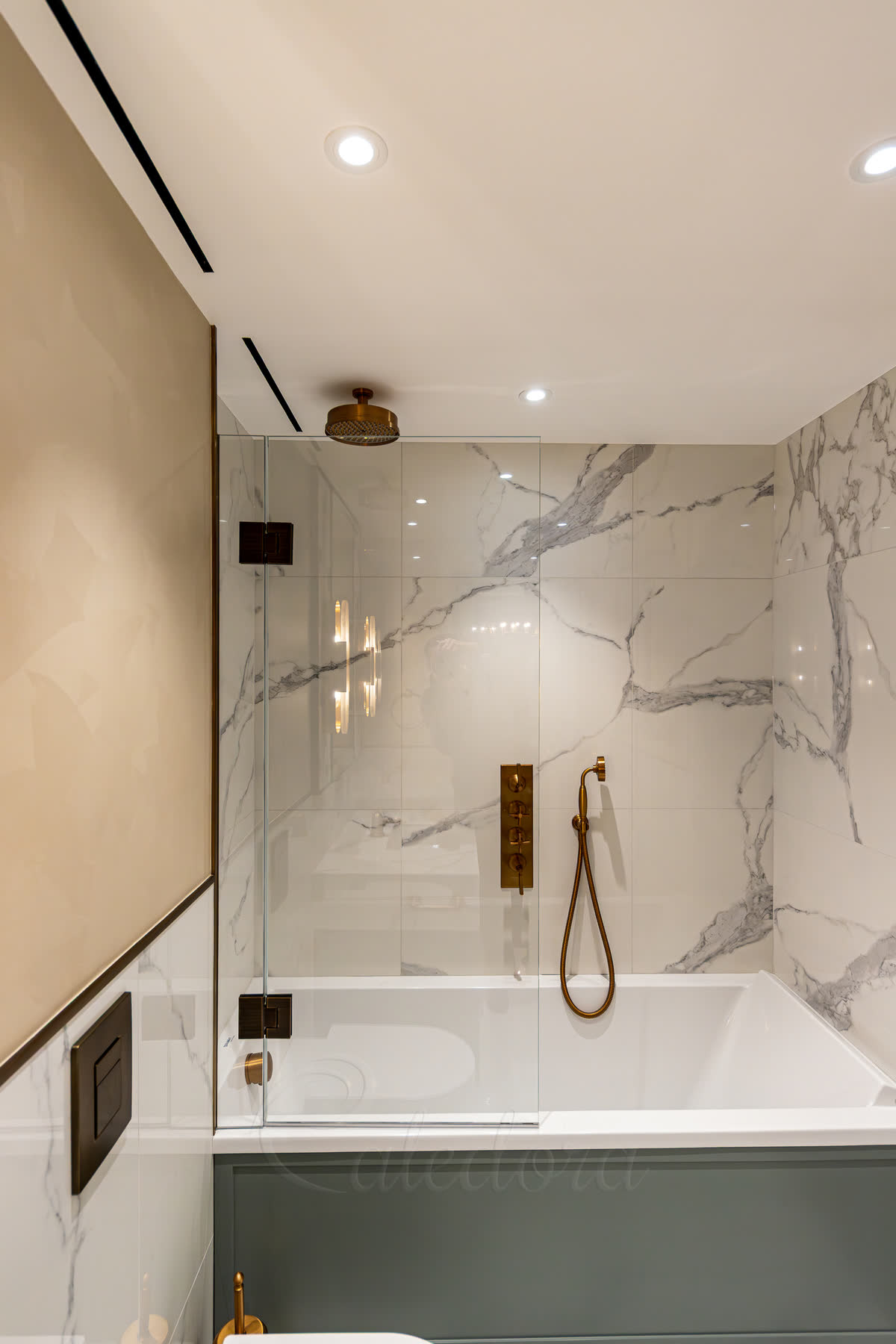 Brass bath screen — frameless glass panel mounted to the wall over the bath with brass brackets