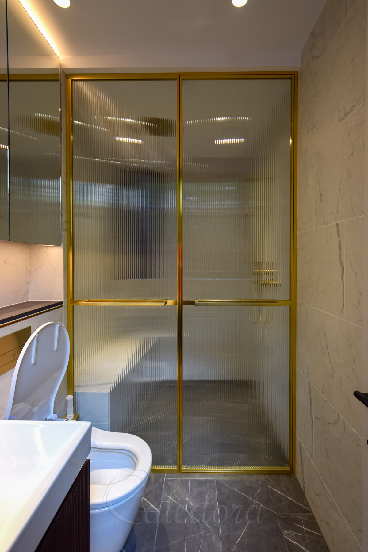 Brass-framed shower door with fluted glass — vertical reeded glass texture inside the brass frame profile