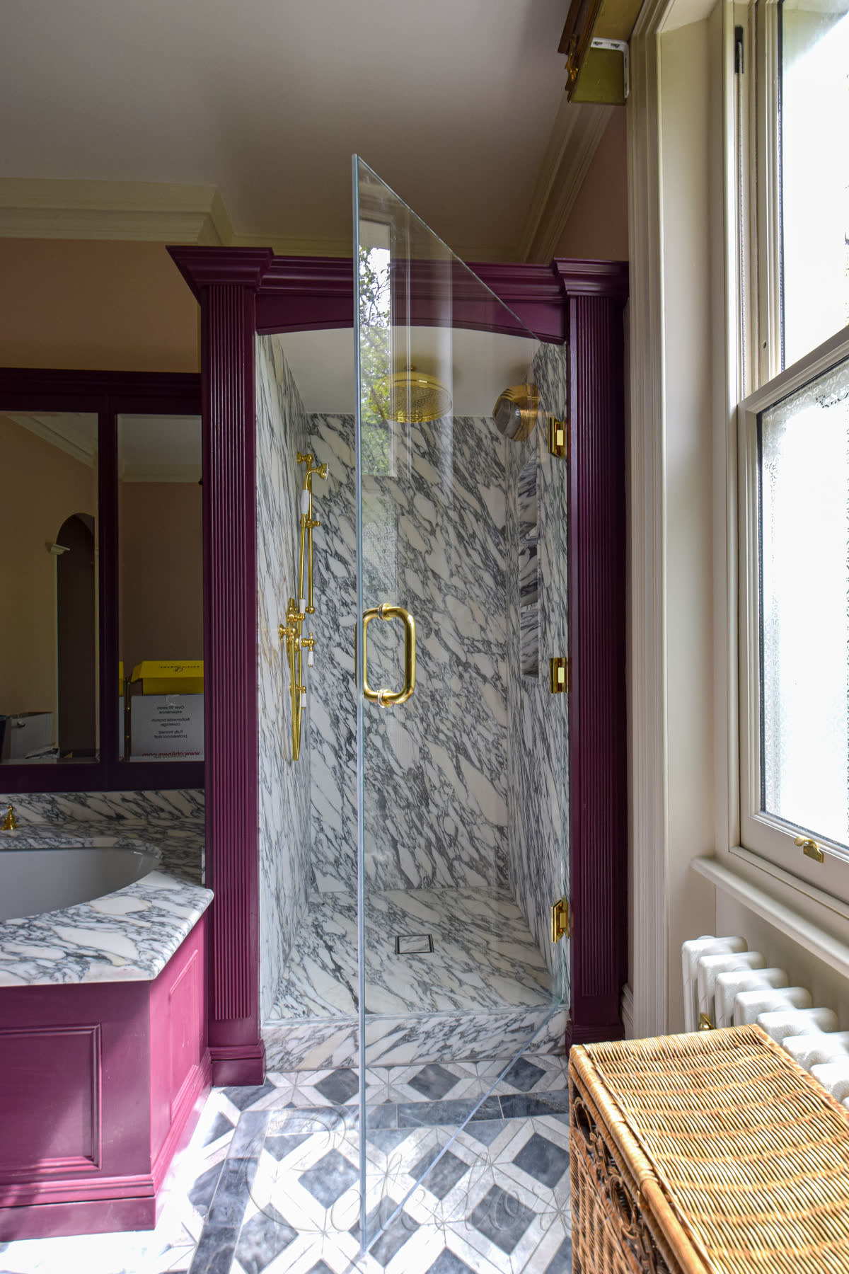 Brass shower door with brass hinges and handle in a period bathroom with deep purple painted wood frame and Arabescato marble interior