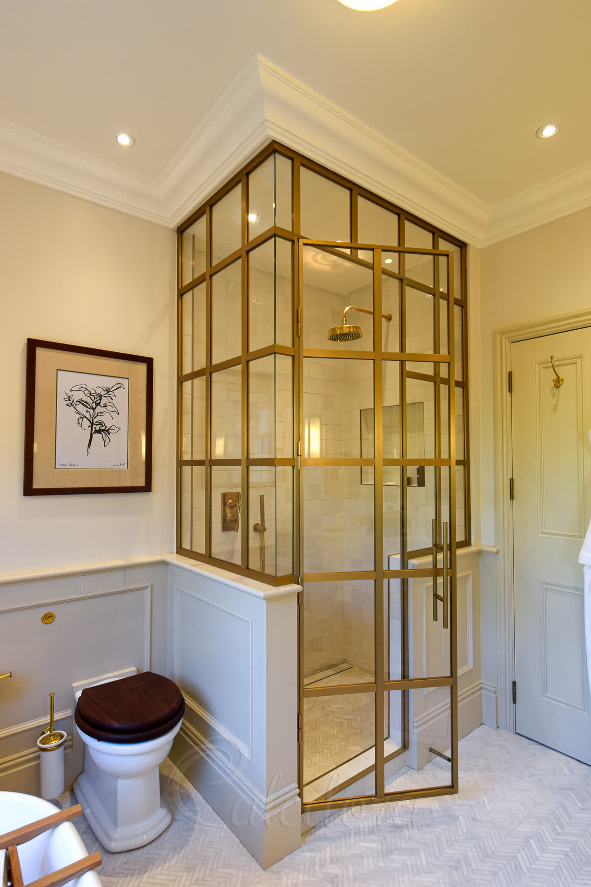 Brushed gold framed corner shower enclosure with grid-style brushed gold frame around clear glass in a period bathroom