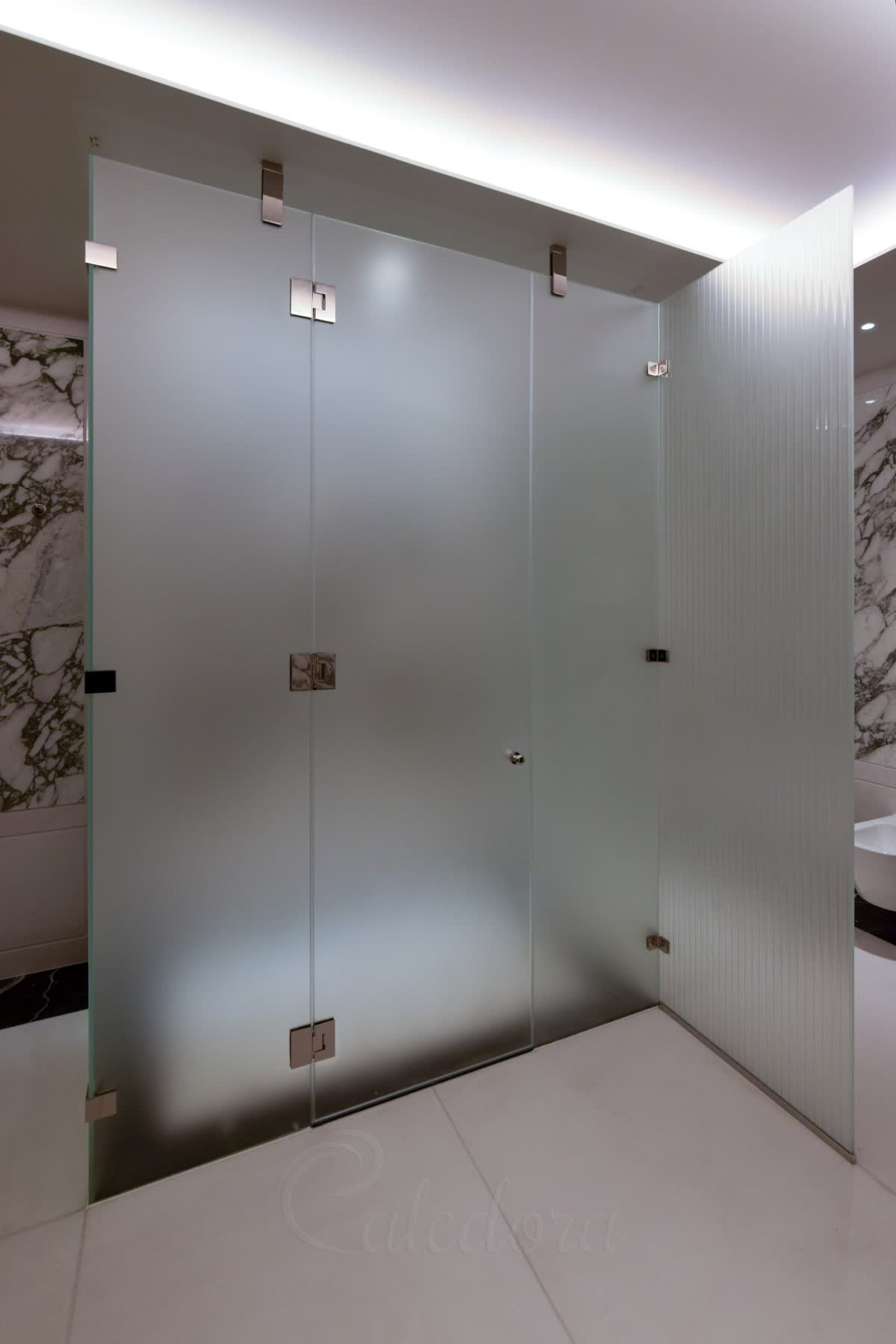 Three-sided frosted glass enclosure with a bespoke fused and sandblasted ribbed panel projecting from one side, with polished nickel brackets against marble