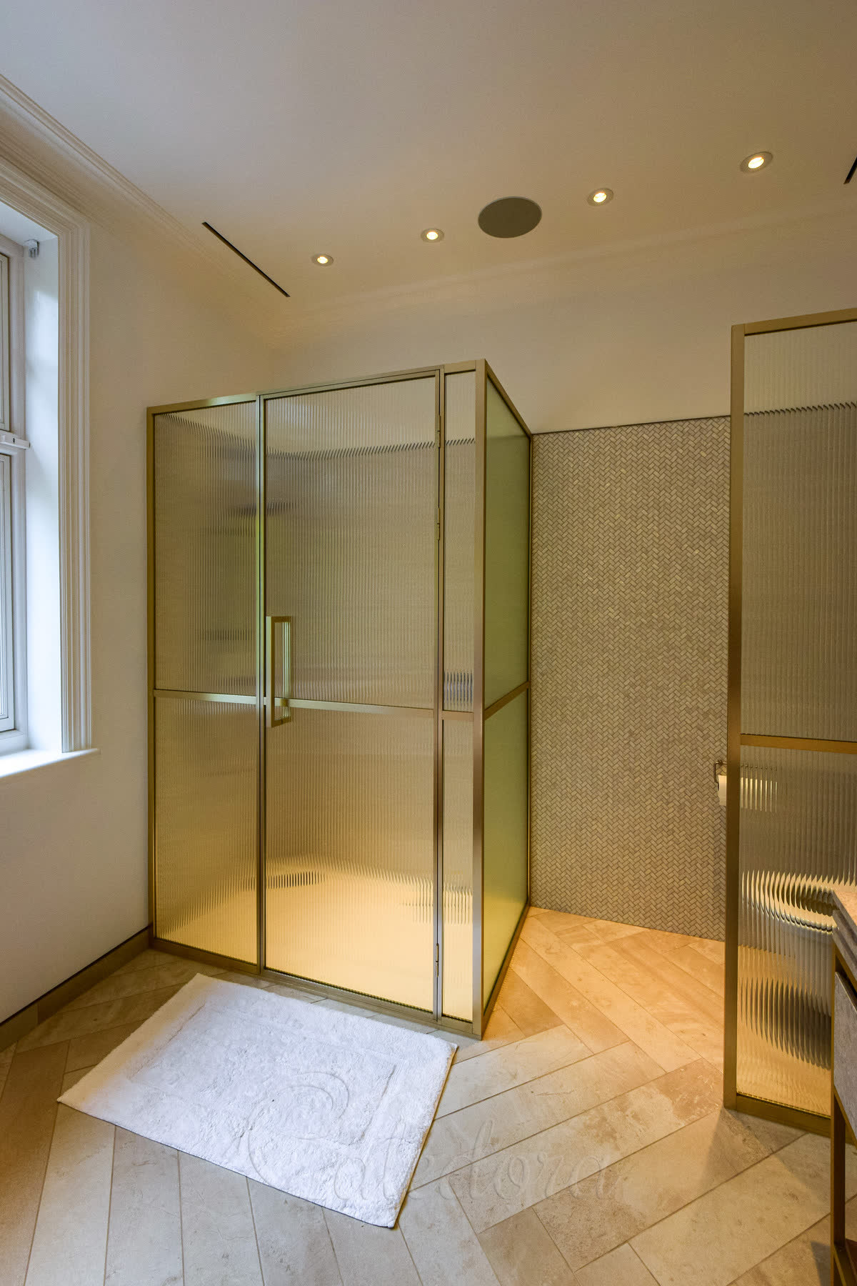 Reeded glass corner shower enclosure framed in brass with matching brass fittings