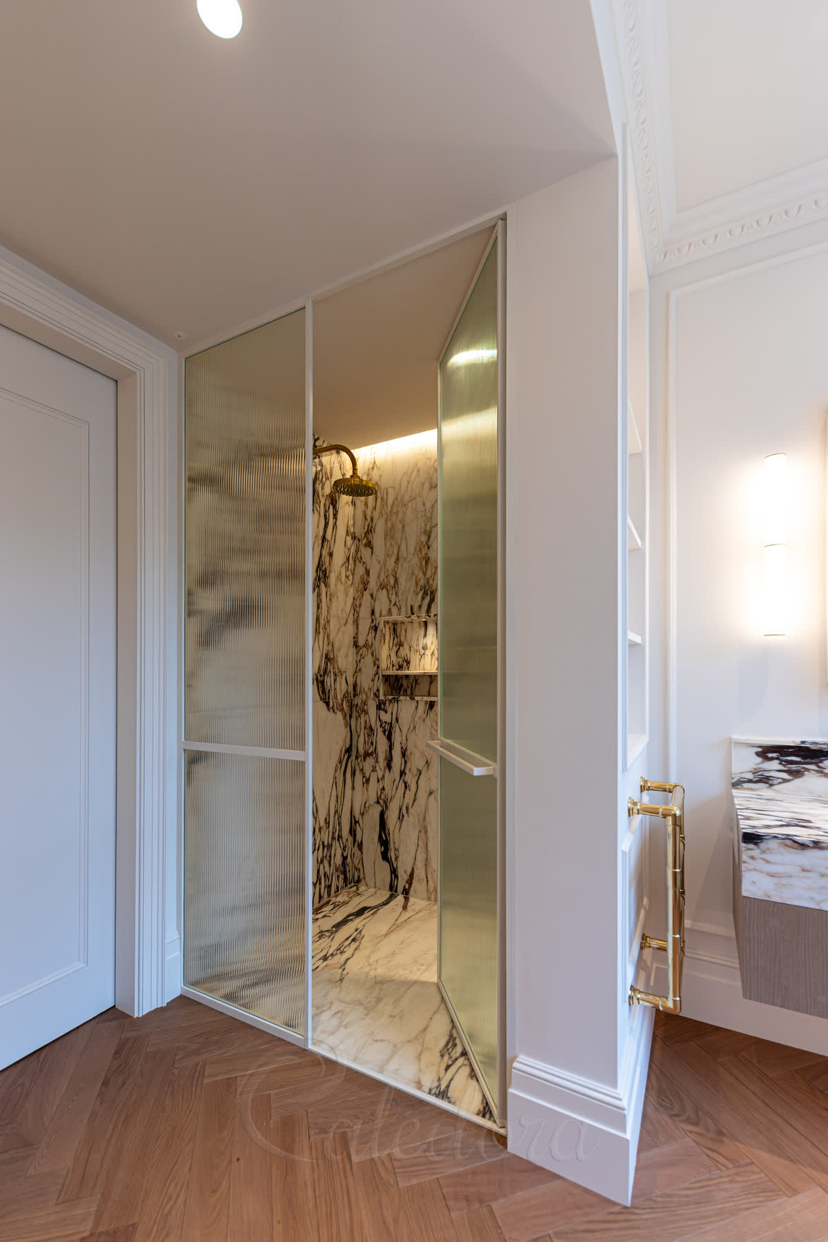Pair of reeded glass doors in white painted frames set into a panelled corridor with a herringbone oak floor