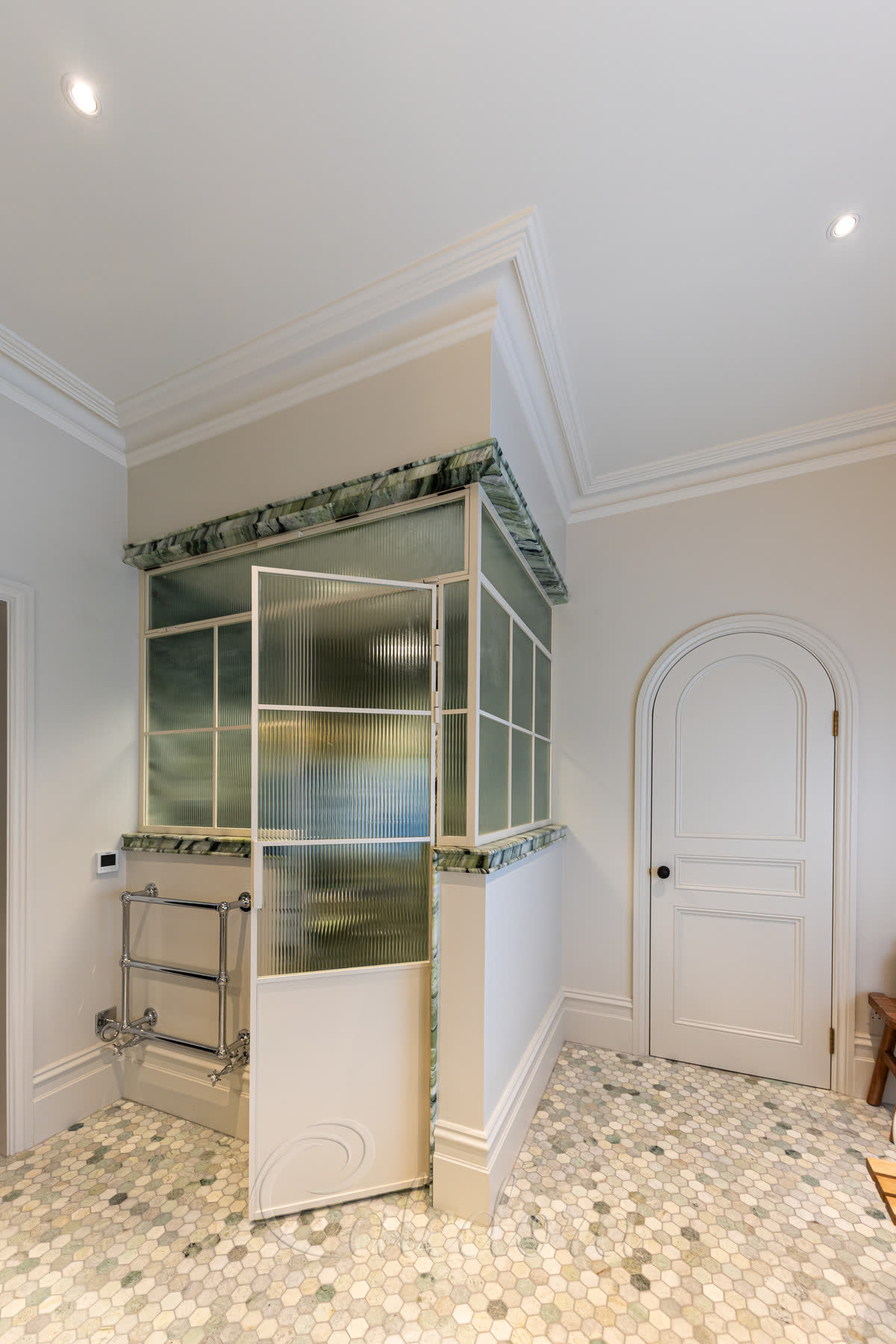 Reeded glass corner shower enclosure in a white grid frame with a green marble top rail, in a period bathroom