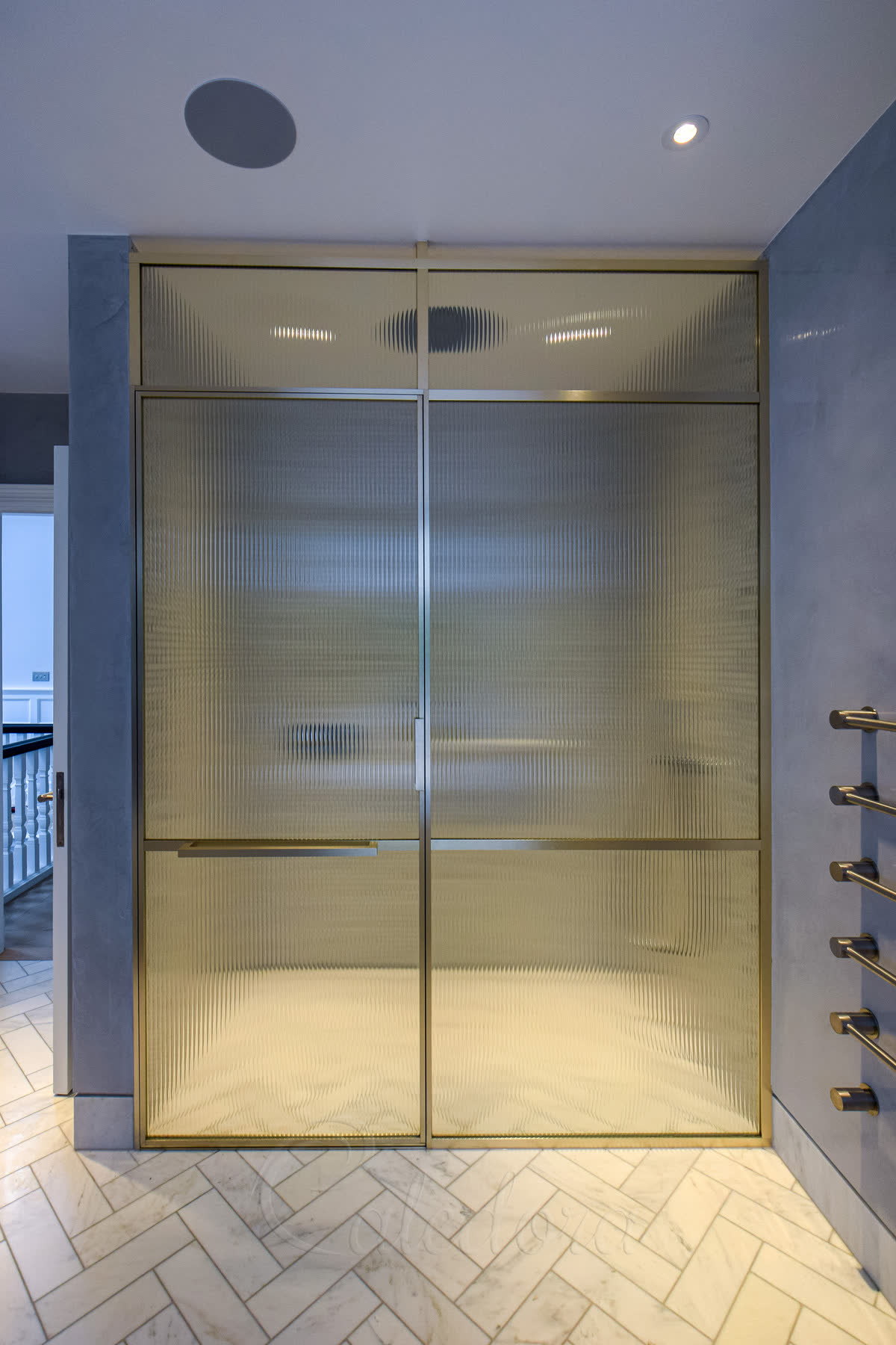 Reeded glass level-access shower with a brass frame and a flush threshold at floor level