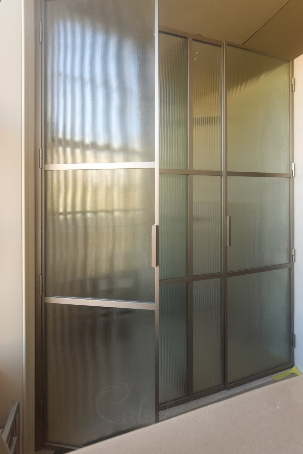 Reeded glass sliding partition in a champagne bronze frame, the sliding leaf running past a fixed panel