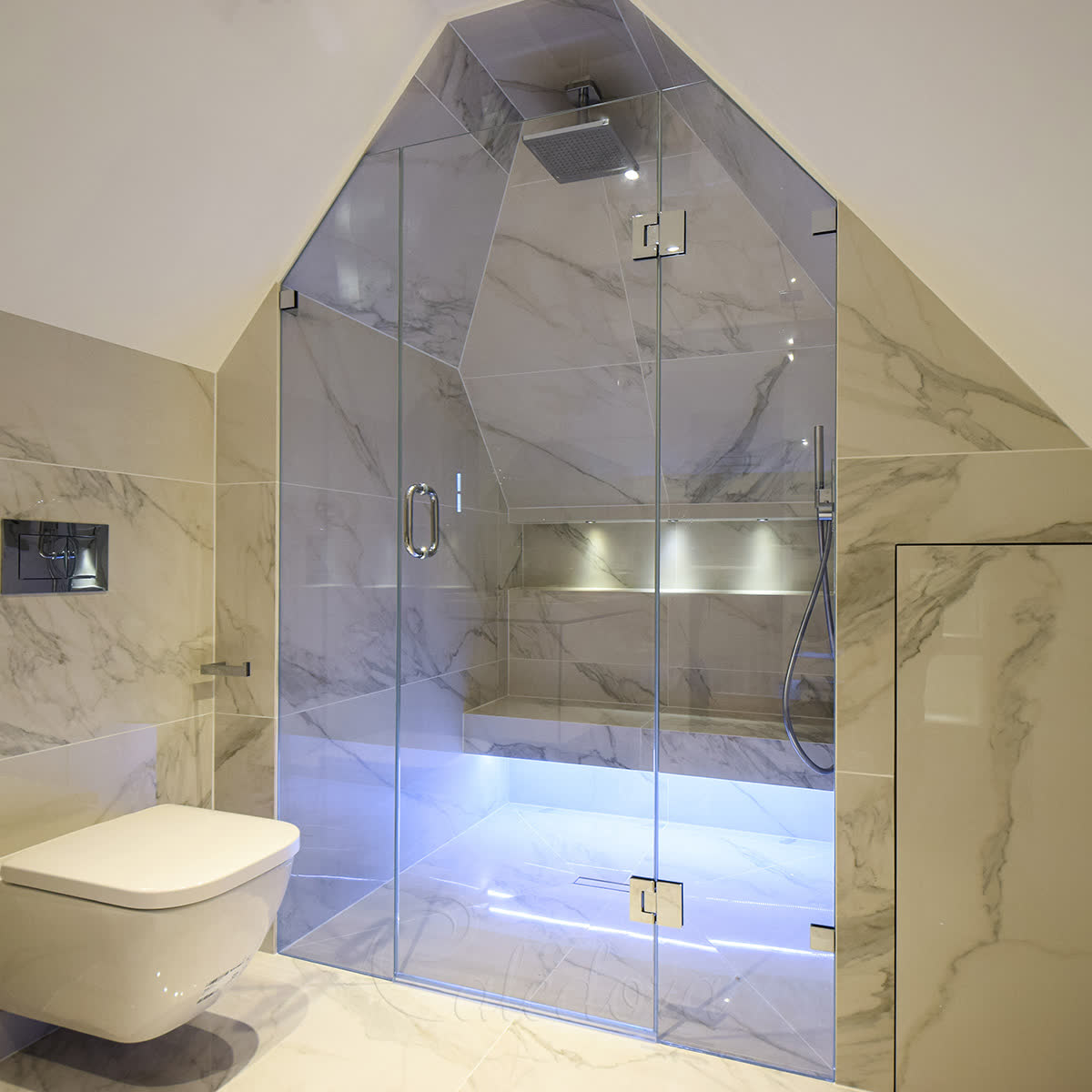 Bespoke glass shape — loft inline shower enclosure with two sides cut to follow sloped ceiling and chrome hinges