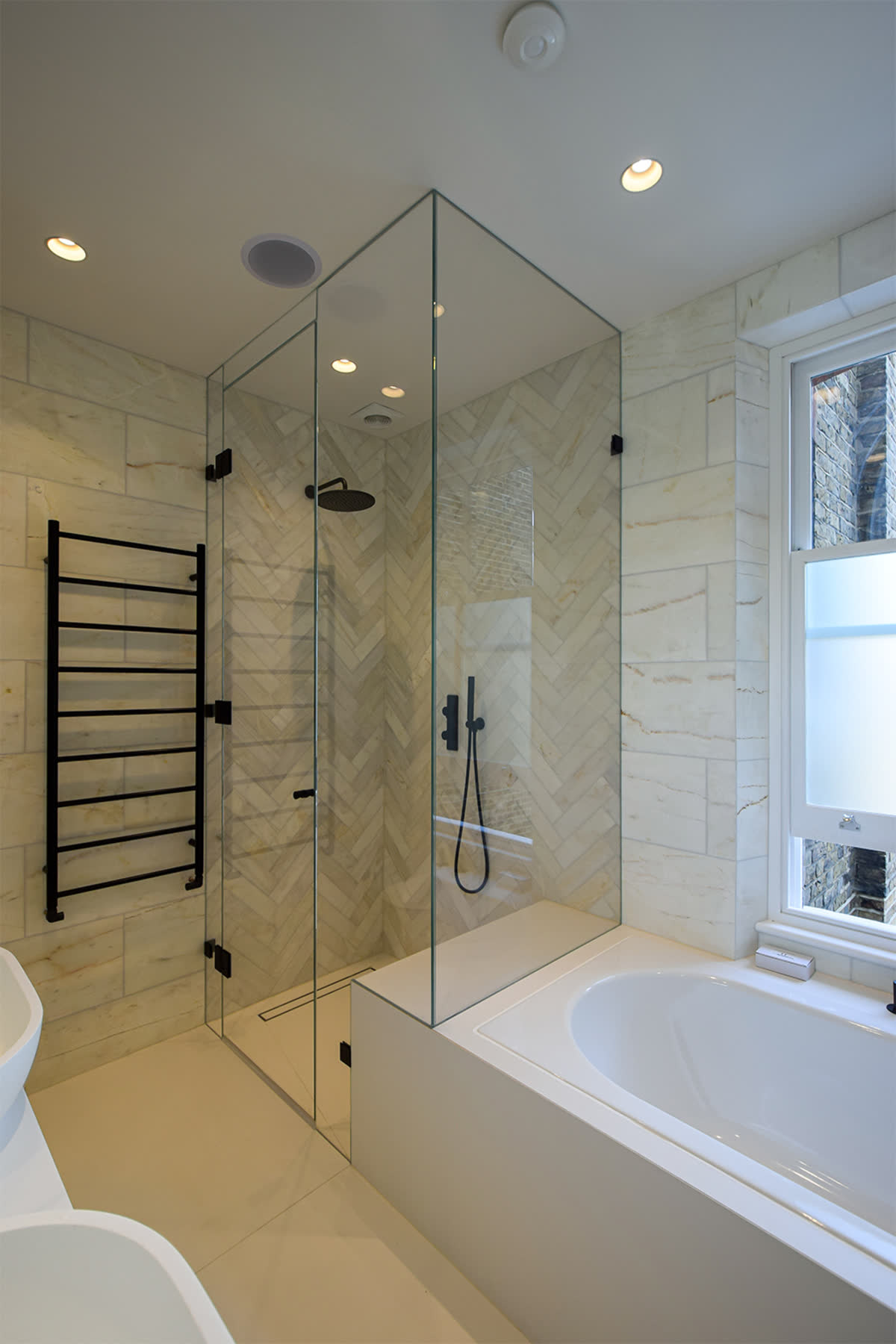 bespoke shower enclosure with black fixtures adjacent to bath