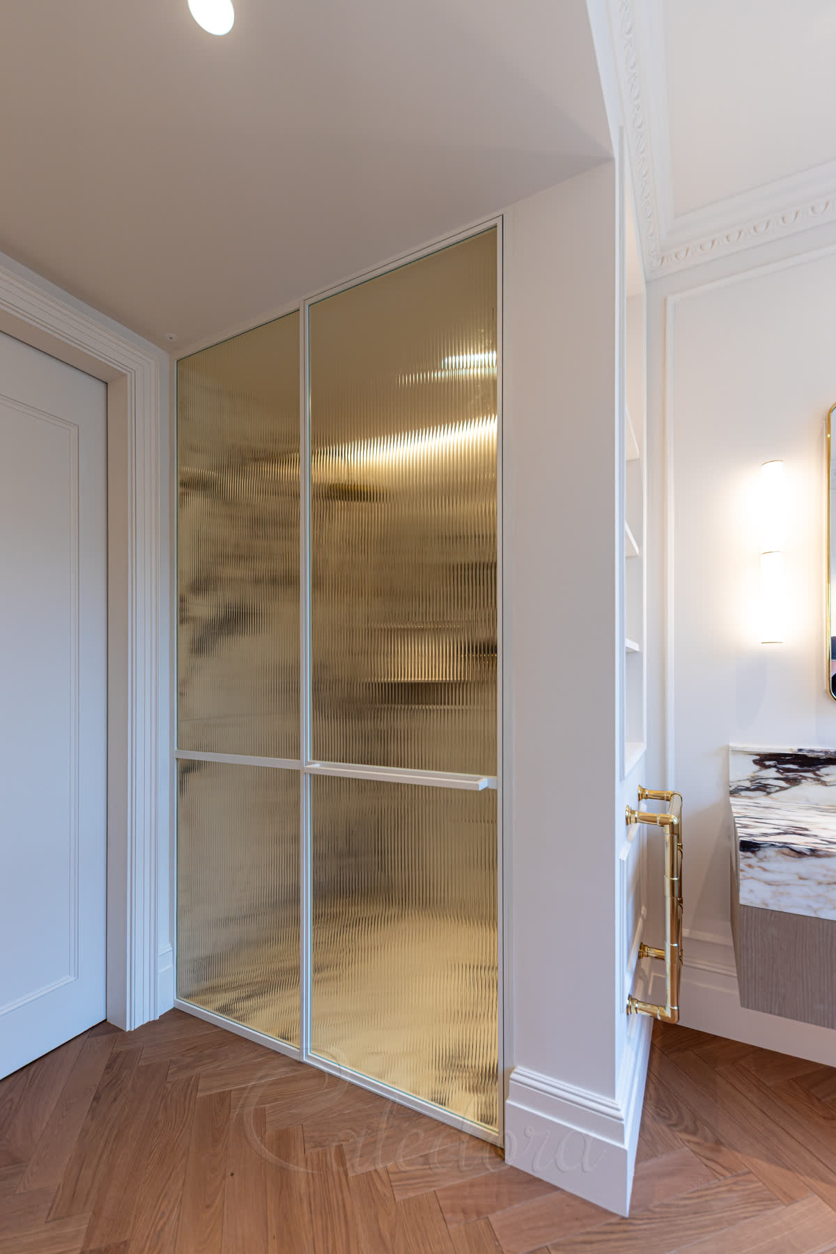 Bespoke reeded-glass shower screen with white frame, brass push-handle and parquet floor in period London bathroom with cornice ceiling
