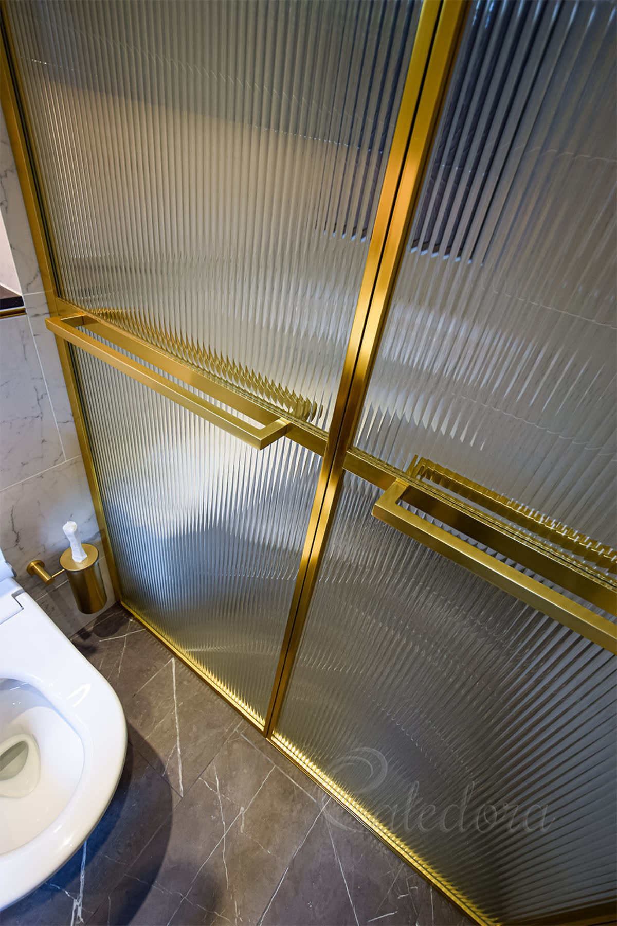 brass finish shower frame surrounding reeded glass panel in shower