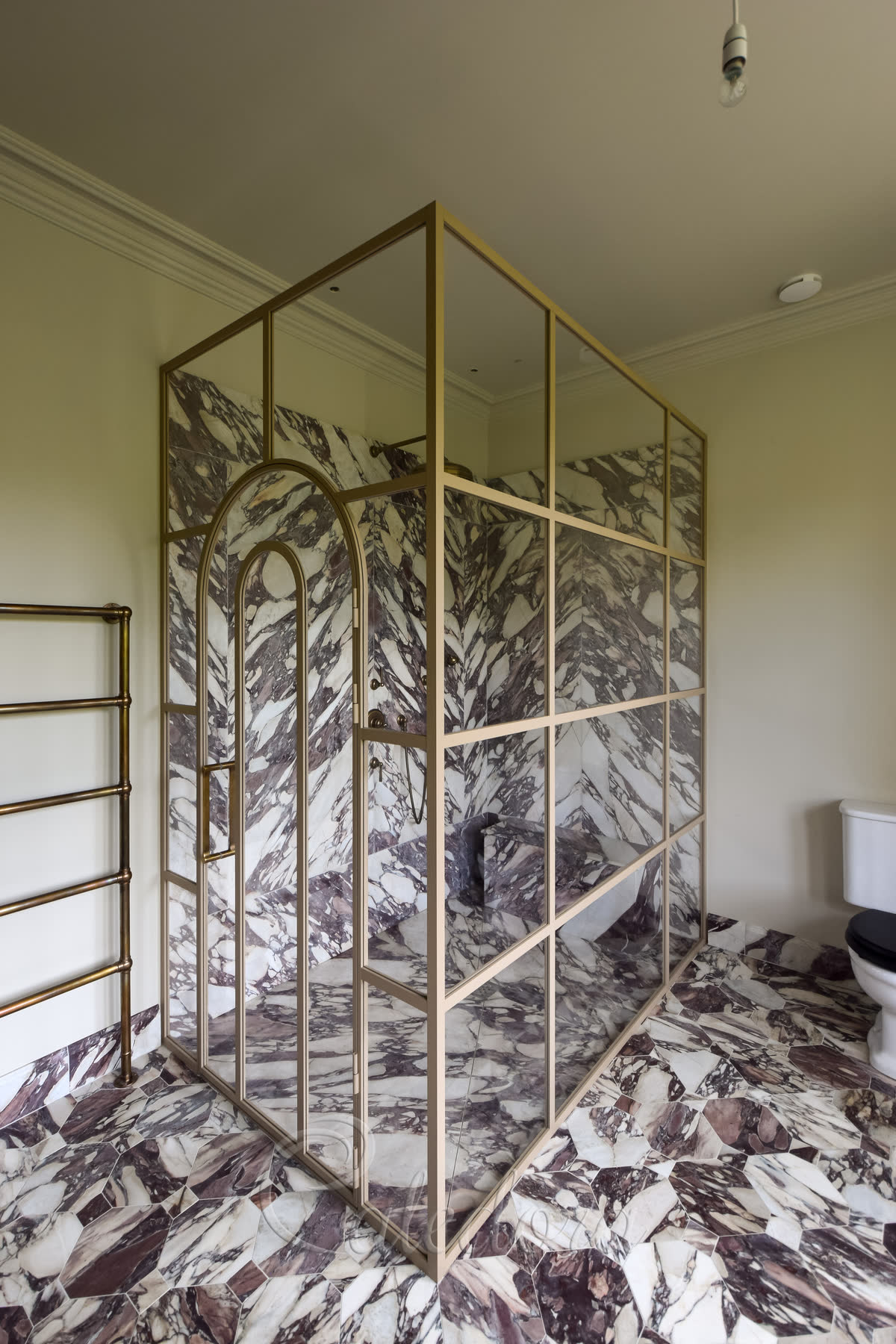 Custom shower enclosure with grid design, unique arched door and beige powder coated frame in luxury marble bathroom