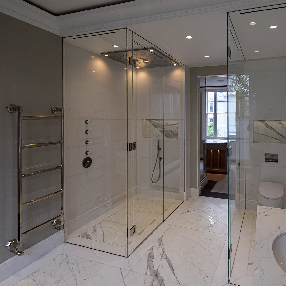 Frameless bespoke shower enclosure with full-height glass, wall-recessed mounting and polished nickel hinges in white marble bathroom