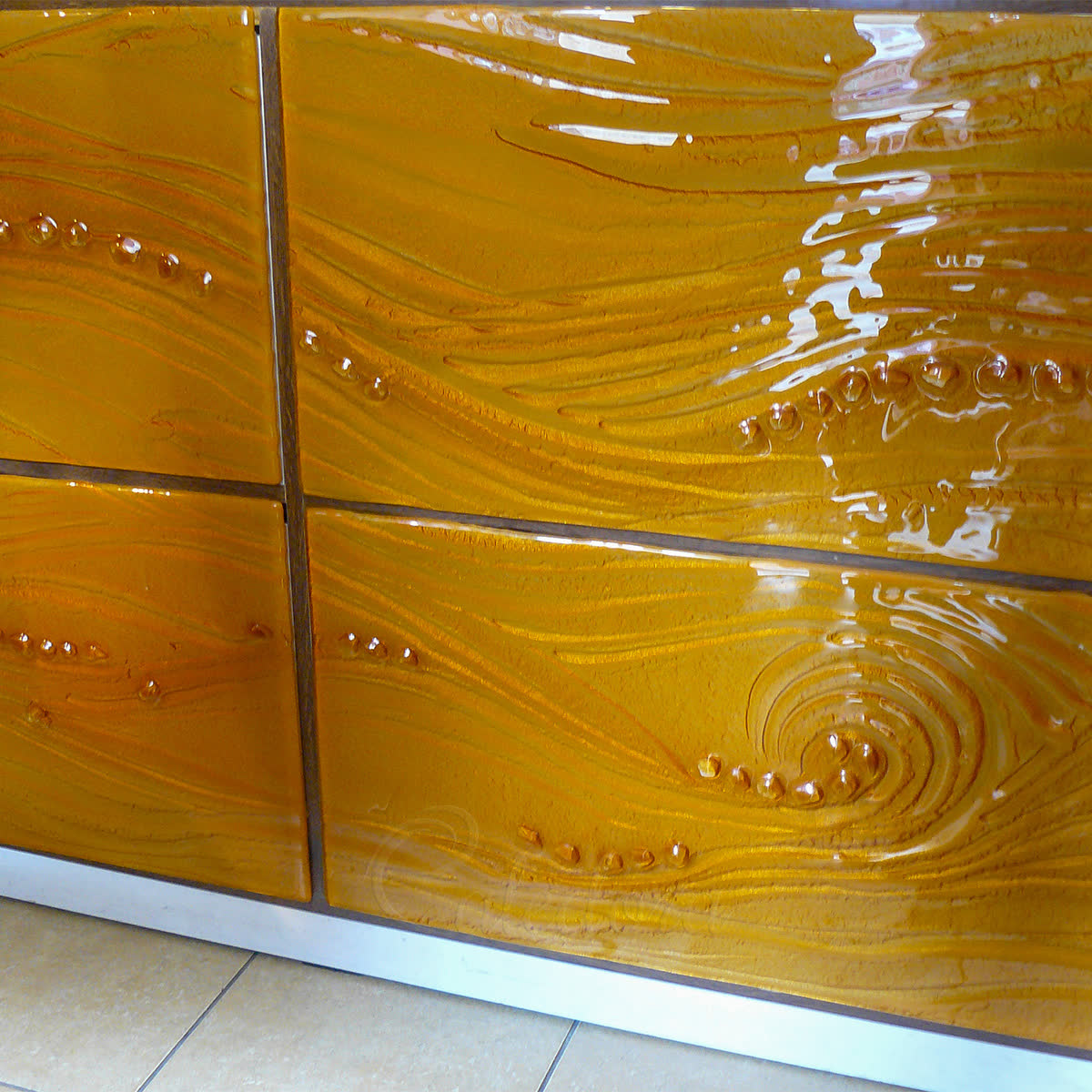 Made-to-measure design glass — kiln-formed fused panels with flowing wave texture and gold back-painting, demonstrating the painted and melted design-glass treatments Caledora can apply to bespoke shower projects