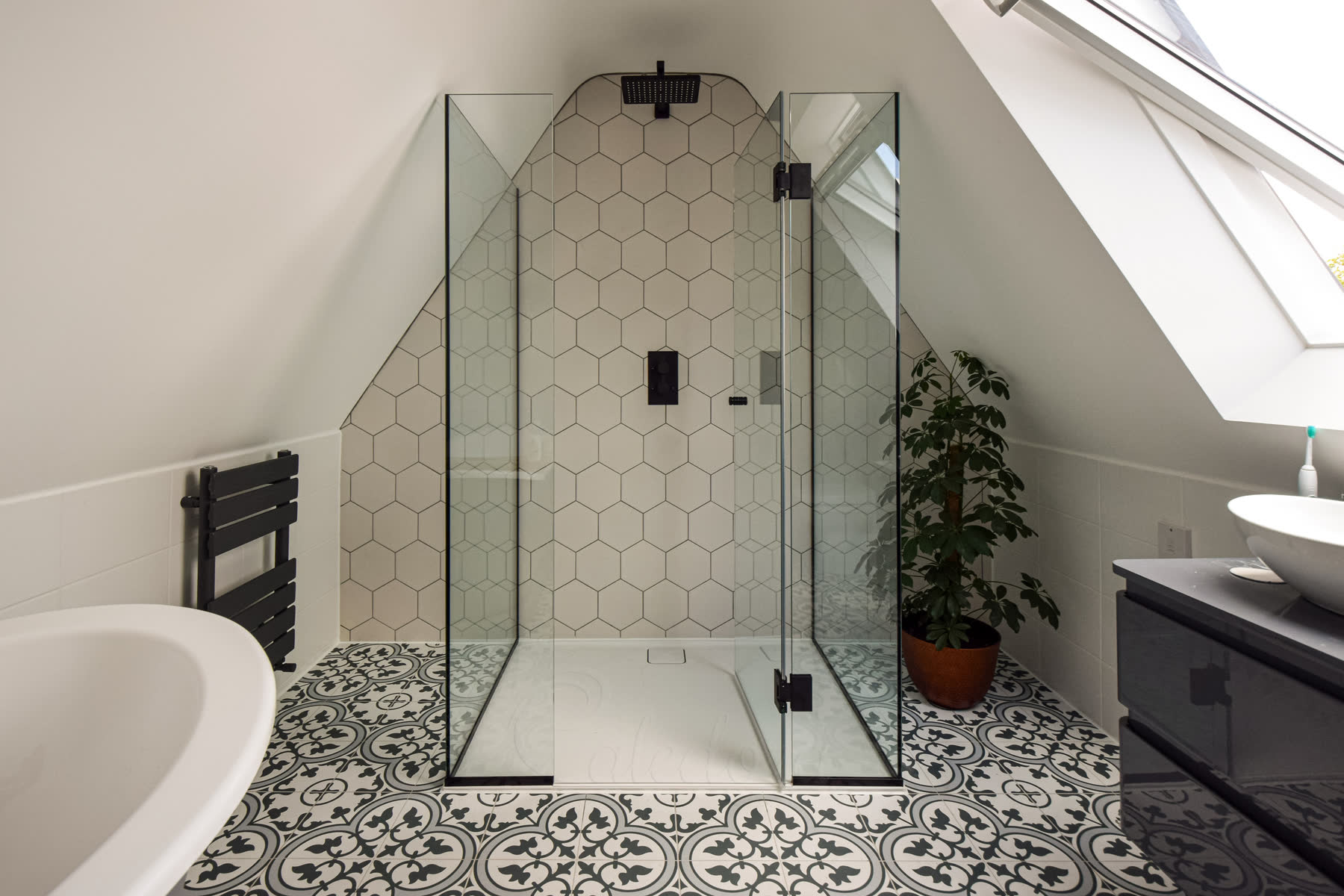Frameless 3-sided shower cubicle with door opened inward showing minimalistic seals on beige tiled bathroom