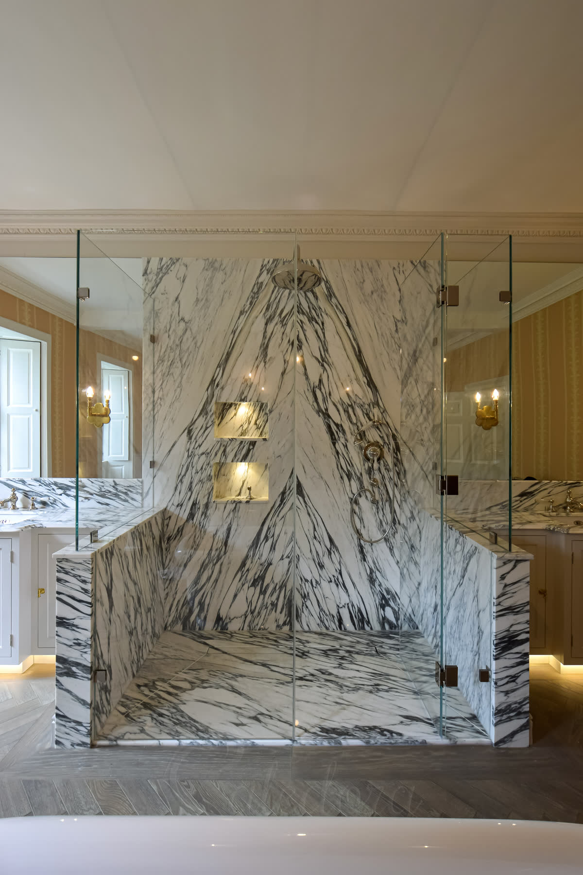 Slim hinged glass door in frameless three-sided shower enclosure with nickel fittings