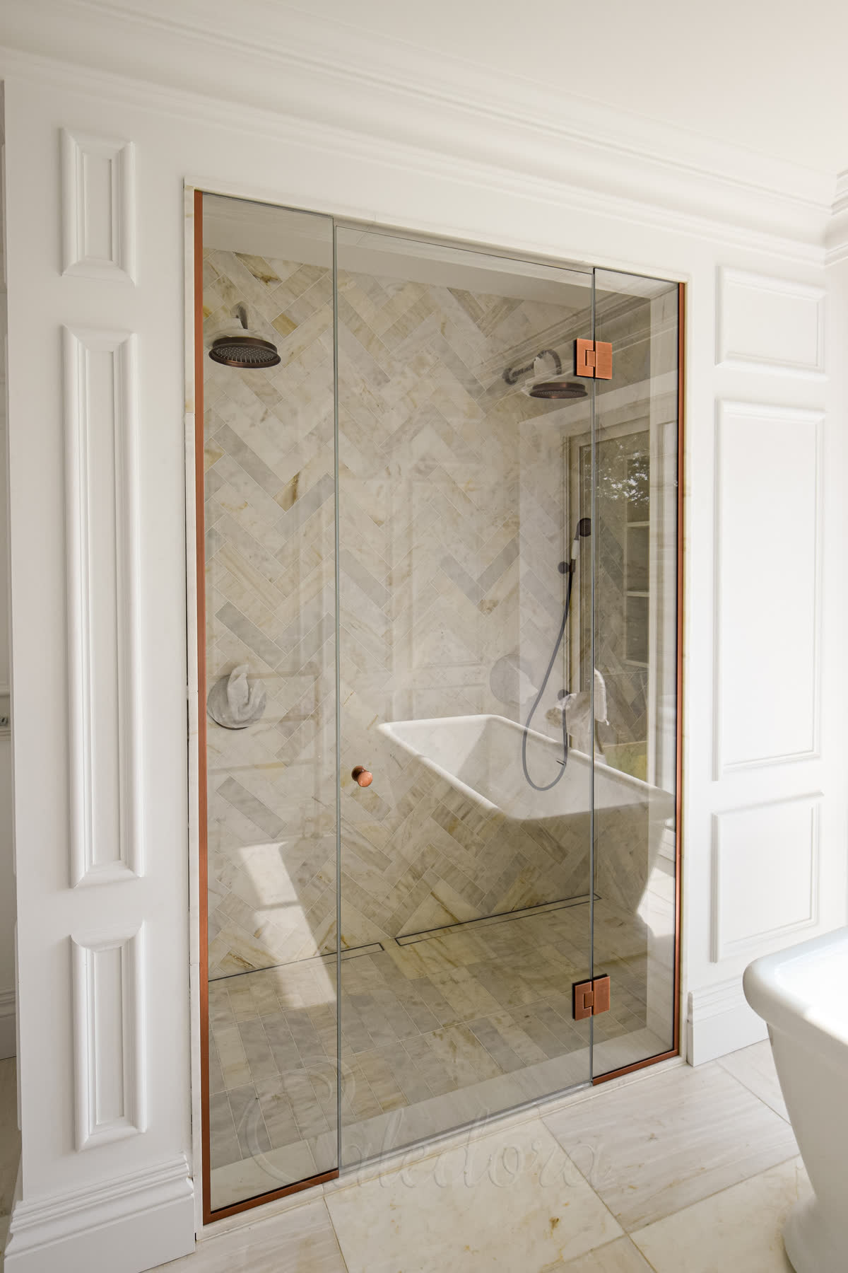 Frameless alcove shower enclosure with copper fixtures in Beaconsfield bathroom, viewed from the left side with closed door aligning with side panels