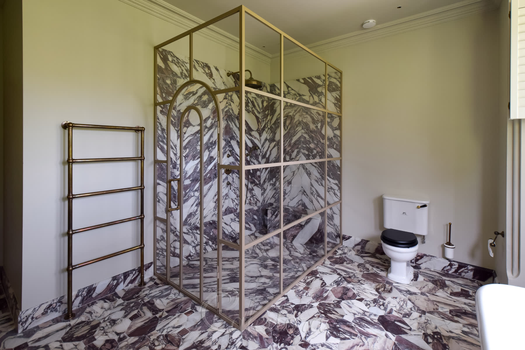 Close-up of beige arched shower door with grid design complementing marble floor