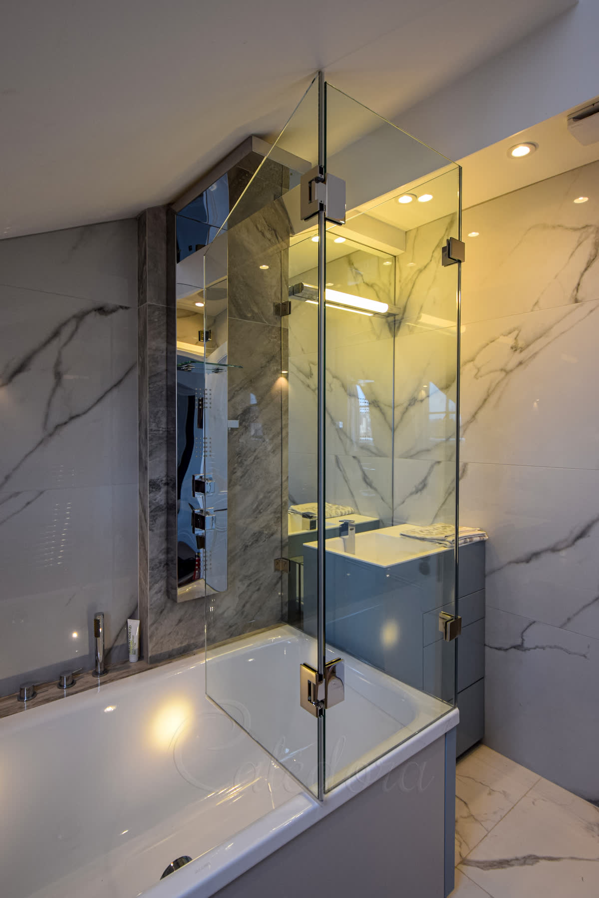 Bath shower enclosure with hinged door and fixed panels creating complete glass enclosure over standard bath in London home