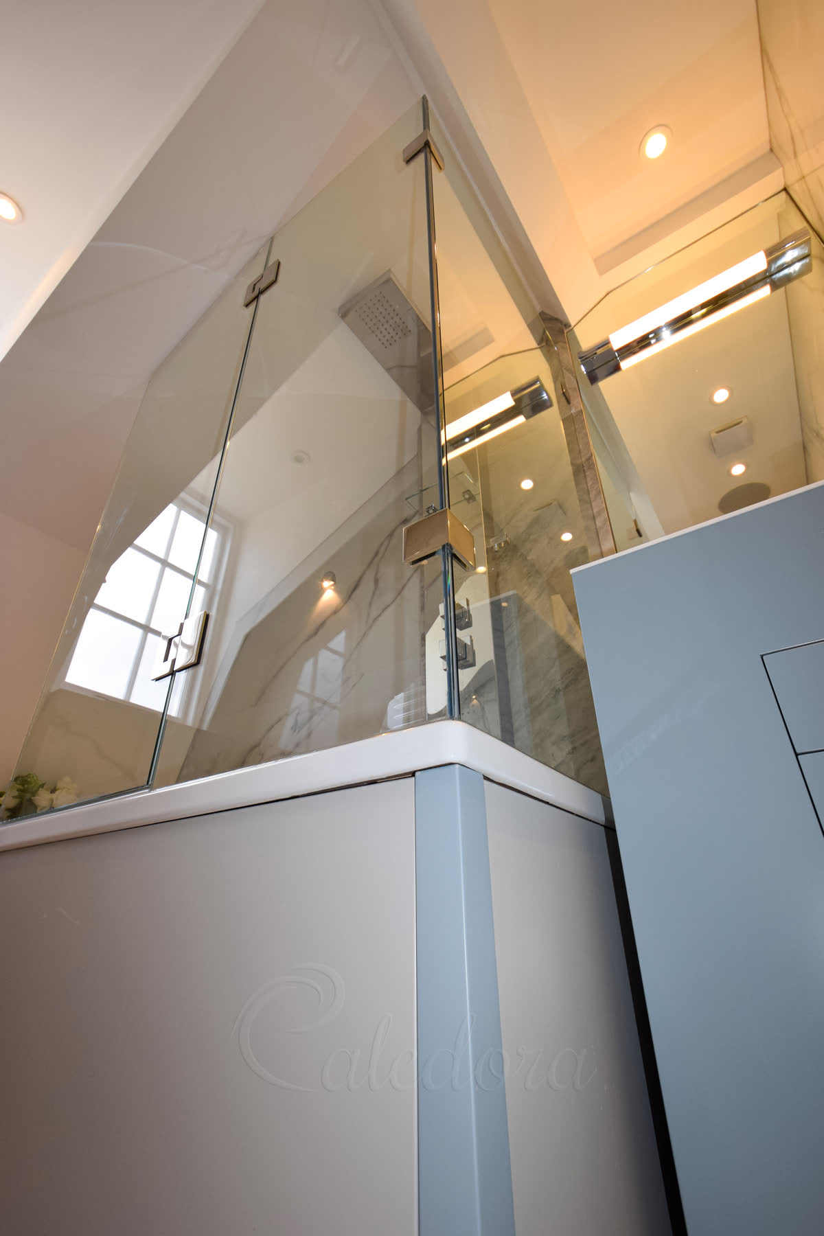 Shower door over bath with sloped ceiling featuring polished nickel hinges and frameless glass design