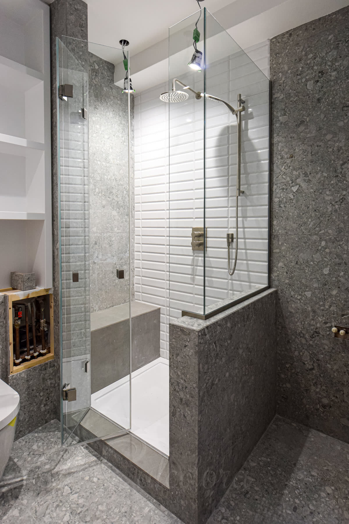 Bi-fold shower door opened outward showing the folding mechanism and dual door knobs