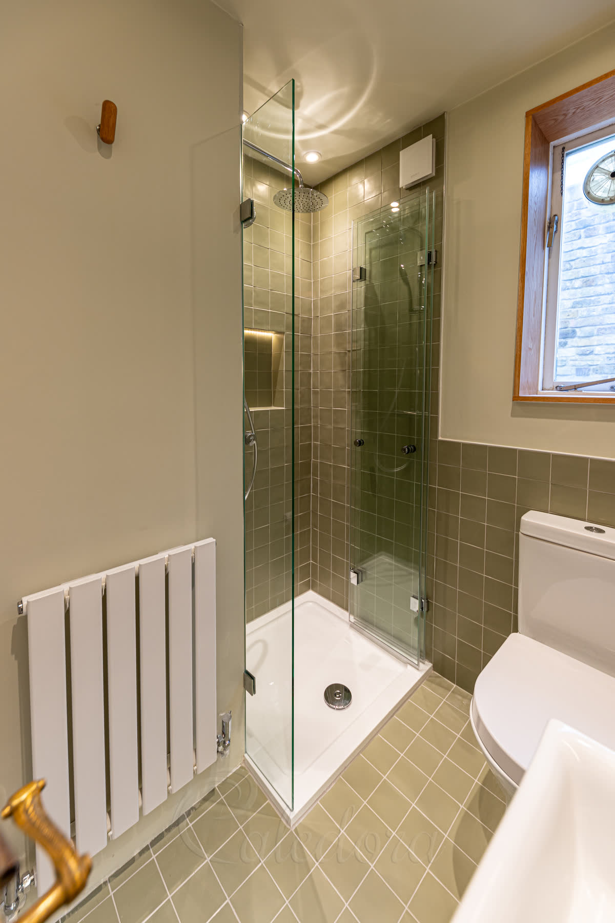 Special Y-brackets holding the fixed screen flush with the tile corner in a frameless shower