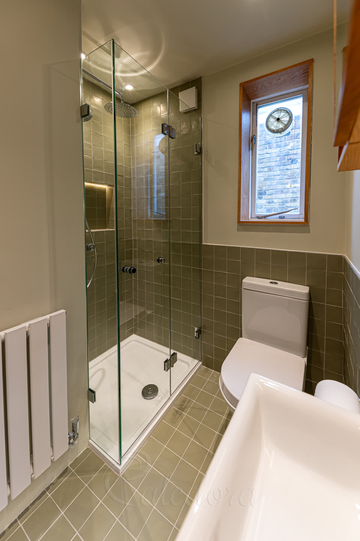 Frameless bifold shower enclosure with clear glass and chrome fittings in a compact London bathroom