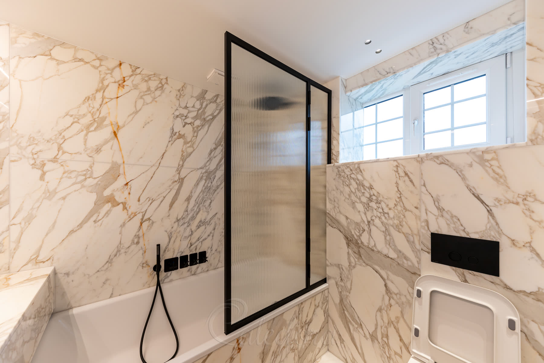 Side view of black bath screen with reeded glass installed over a white bathtub