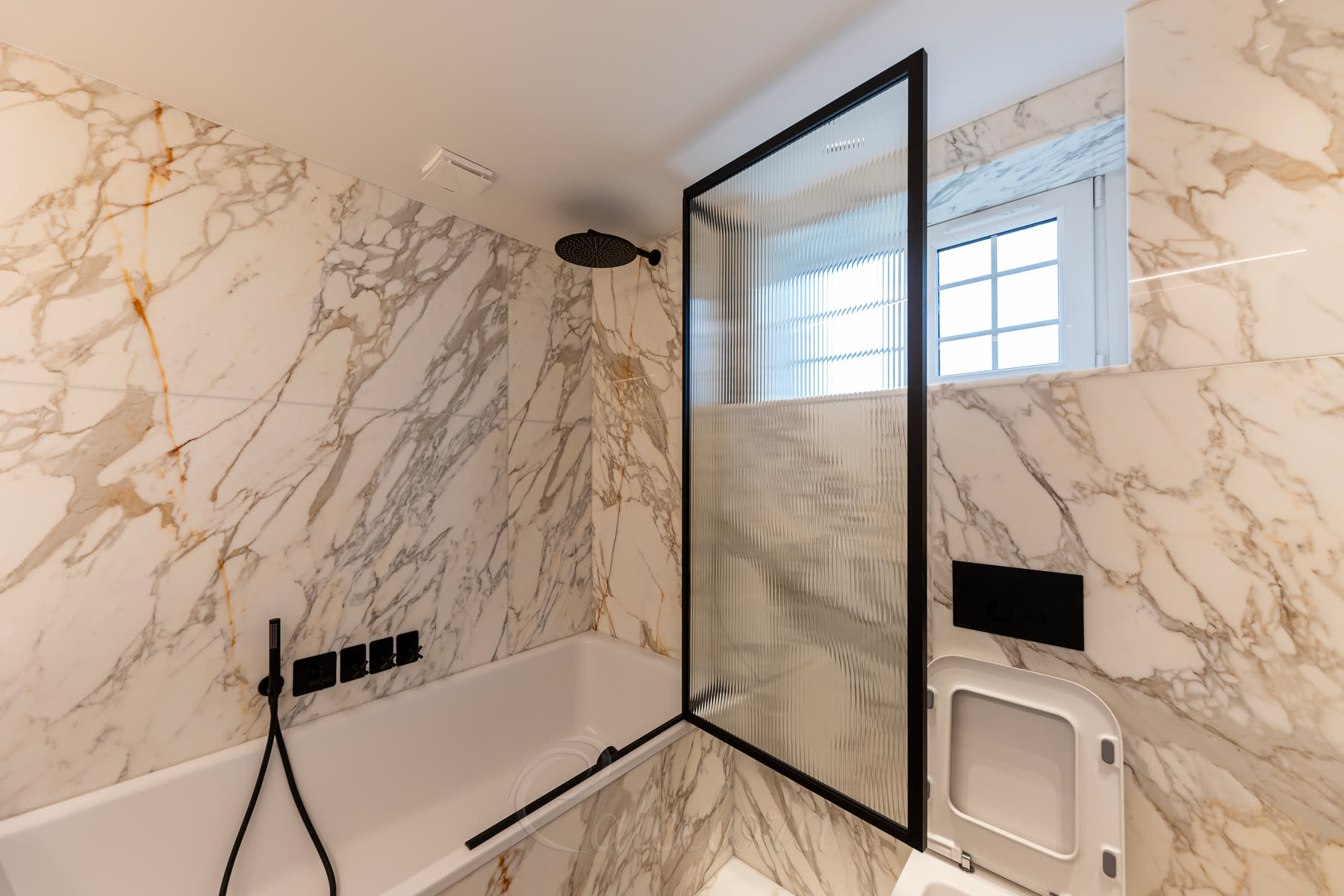 Black bath screen with textured reeded glass showcasing the folding mechanism