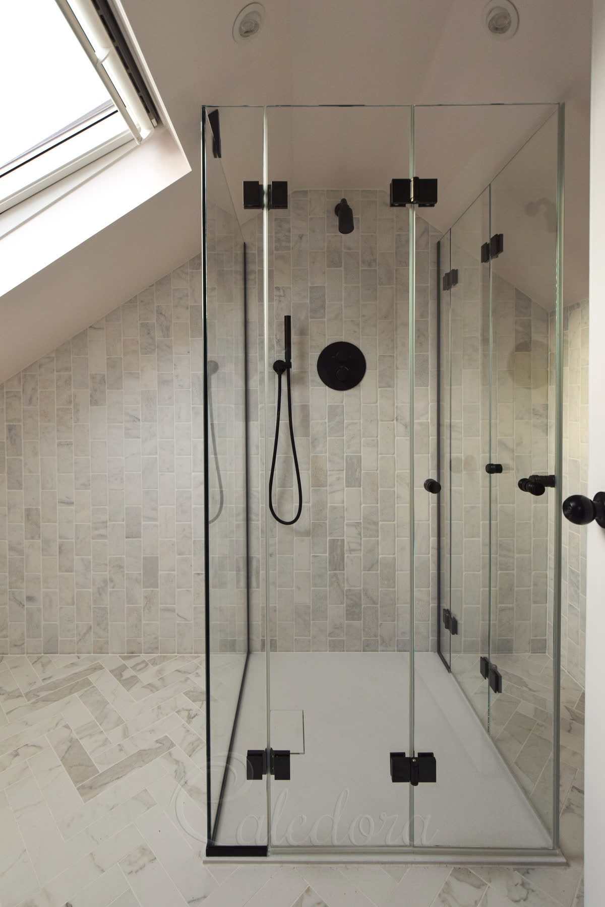 Black bifold shower door in corner enclosure with ultra clear glass in a small loft bathroom