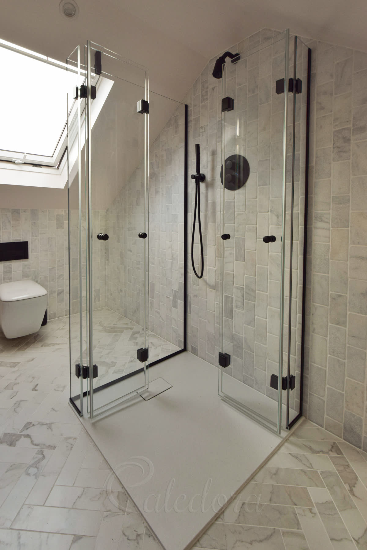 Black corner bifold shower enclosure with custom arm, spring hinges, and slim fixings installed in loft bathroom