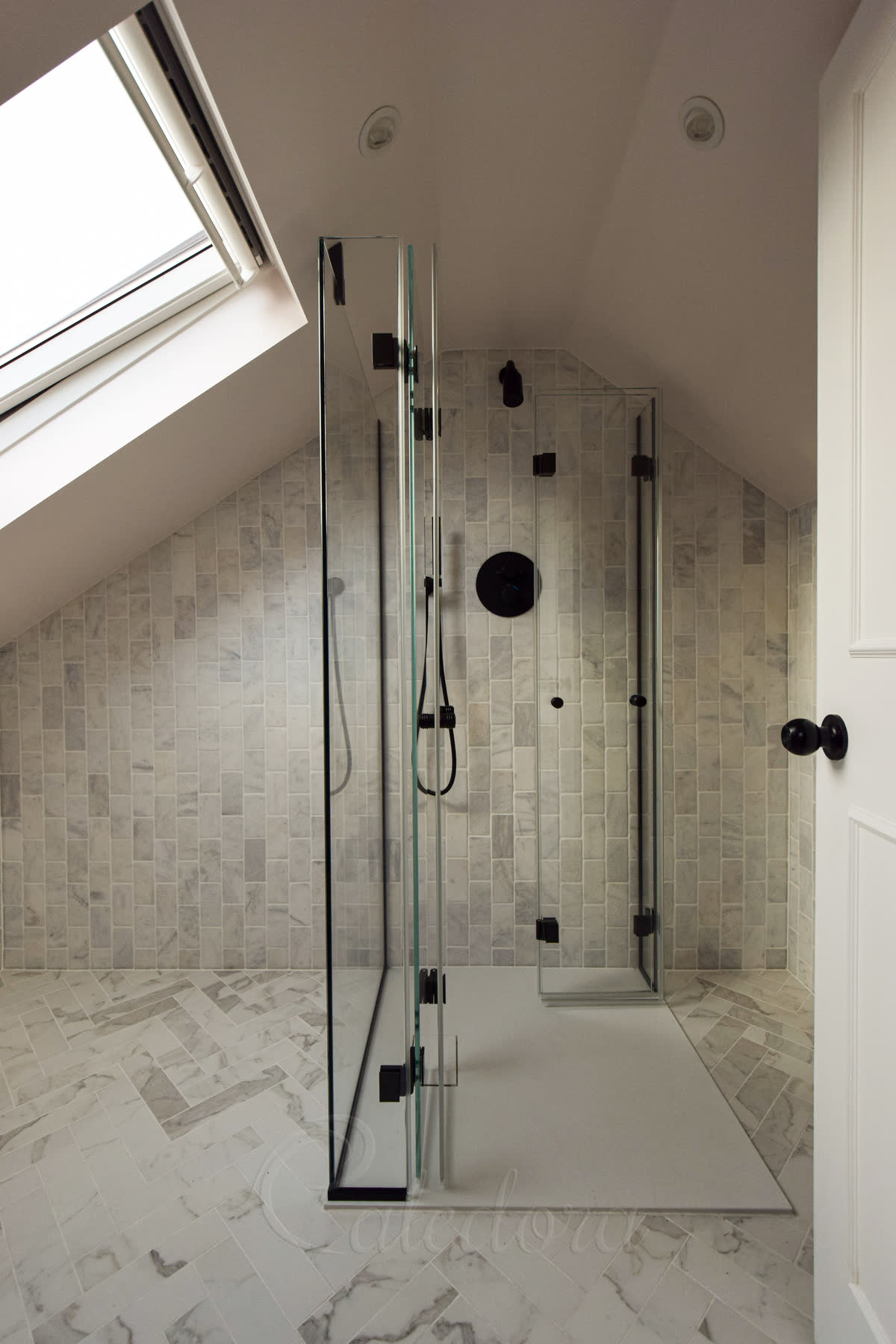 Black bifold shower door with spring-loaded hinges and minimal seals in loft bathroom