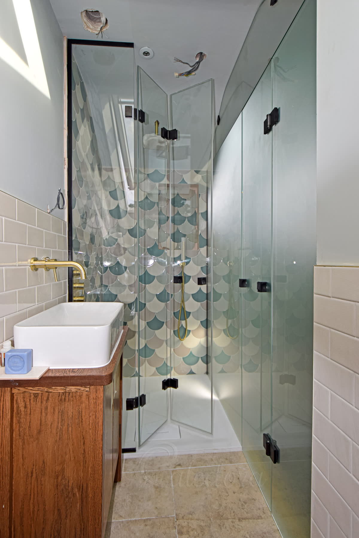 Black bifold shower doors partially open showing folding mechanism and vanity unit