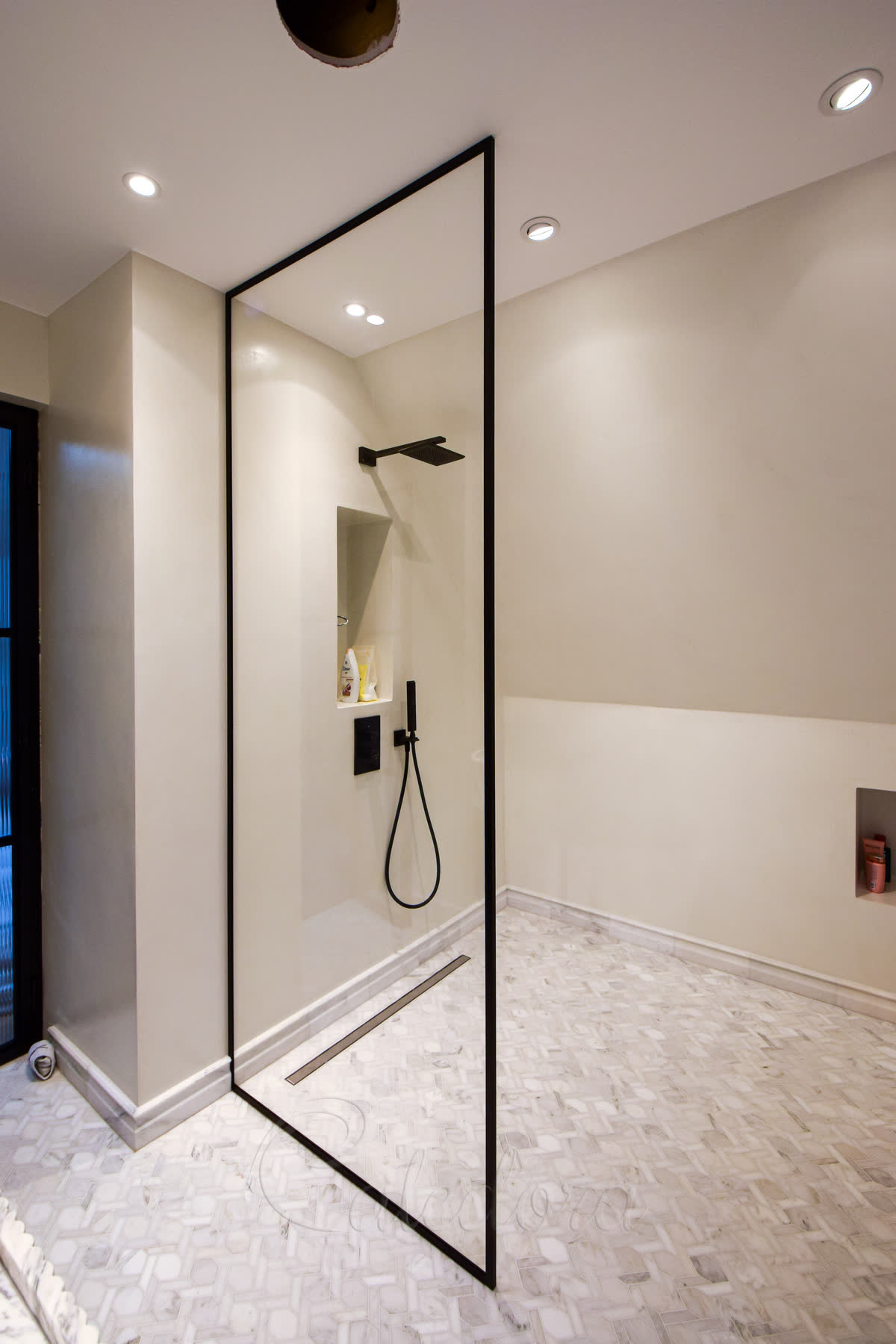 Black framed walk-in shower screen with ultra-clear glass against microcement walls in London bathroom