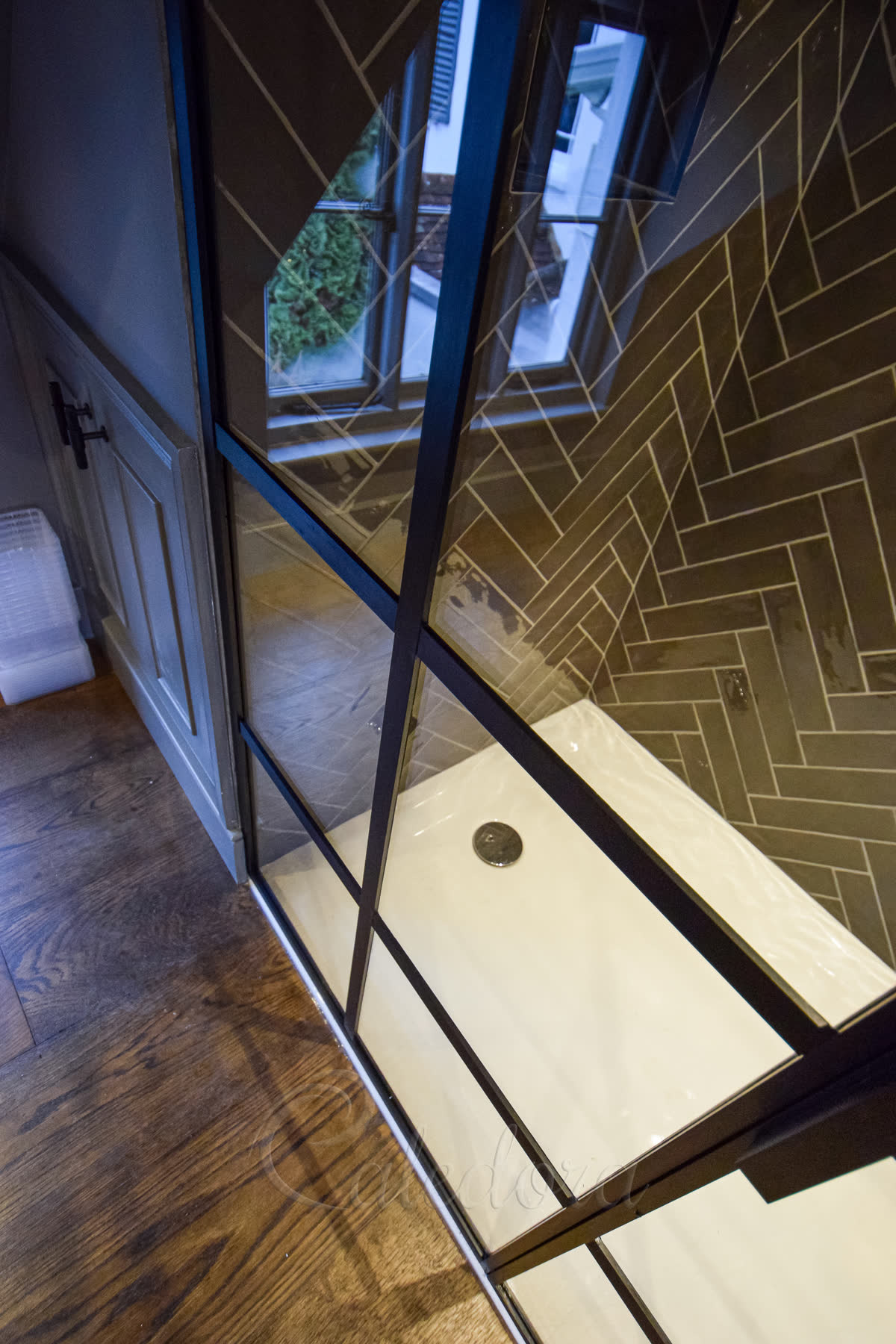 Close-up view of black frame shower door with protruding middle bars and geometric grid design