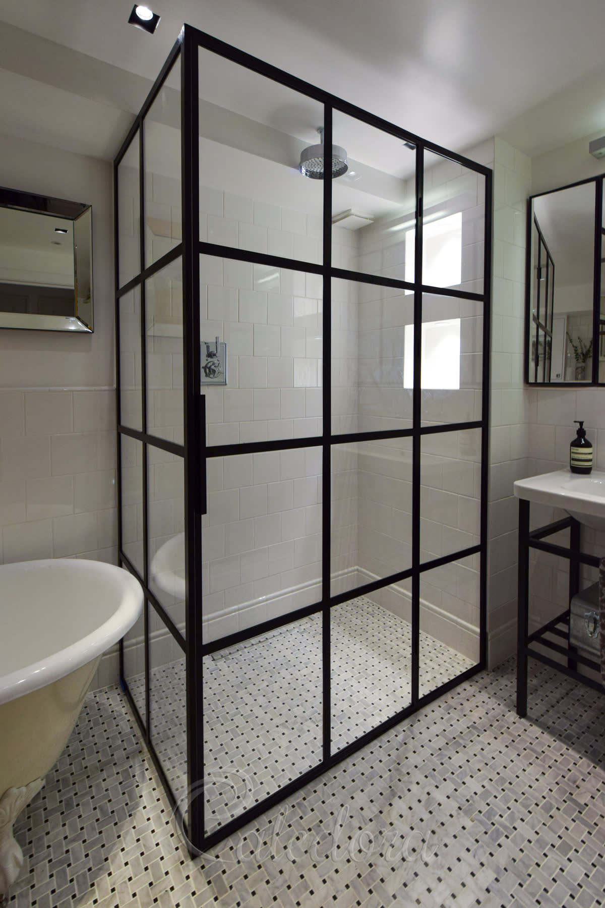 Corner installation of black framed shower with geometric grid pattern and swing door