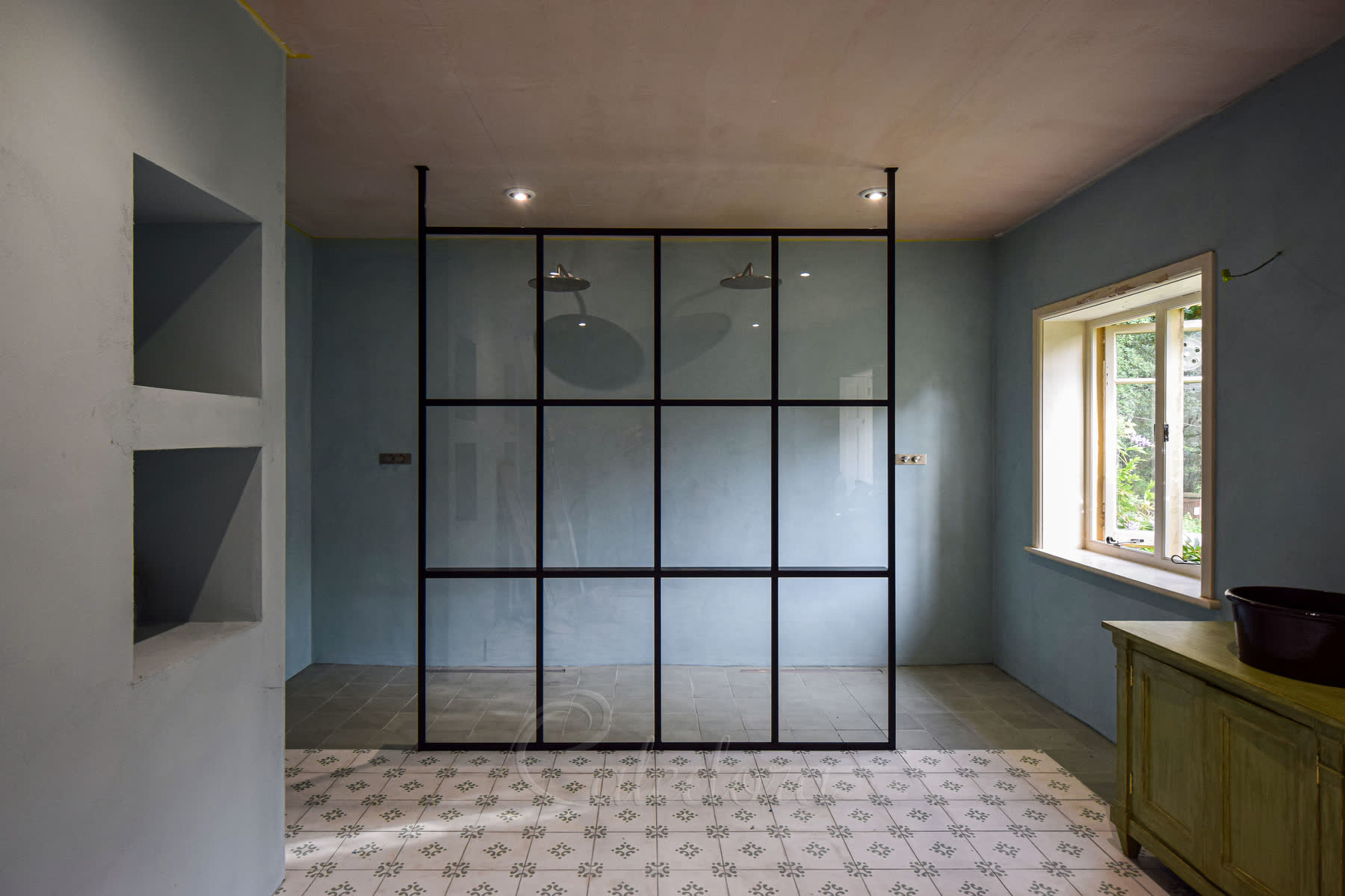 Front view of bespoke black grid shower enclosure with double shower setup and patterned floor tiles