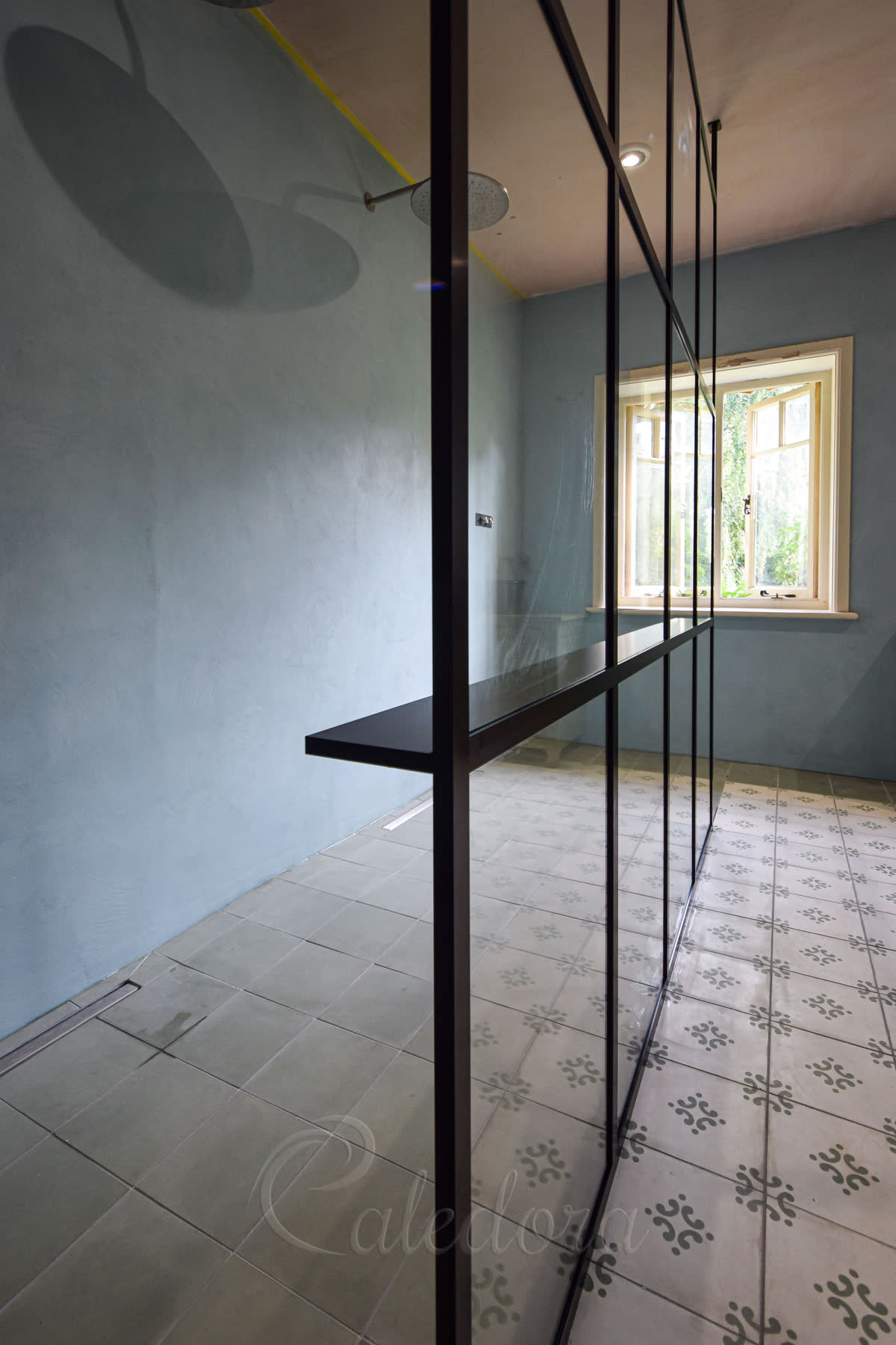 Close-up of the custom black shelf integrated within the framed shower screen design