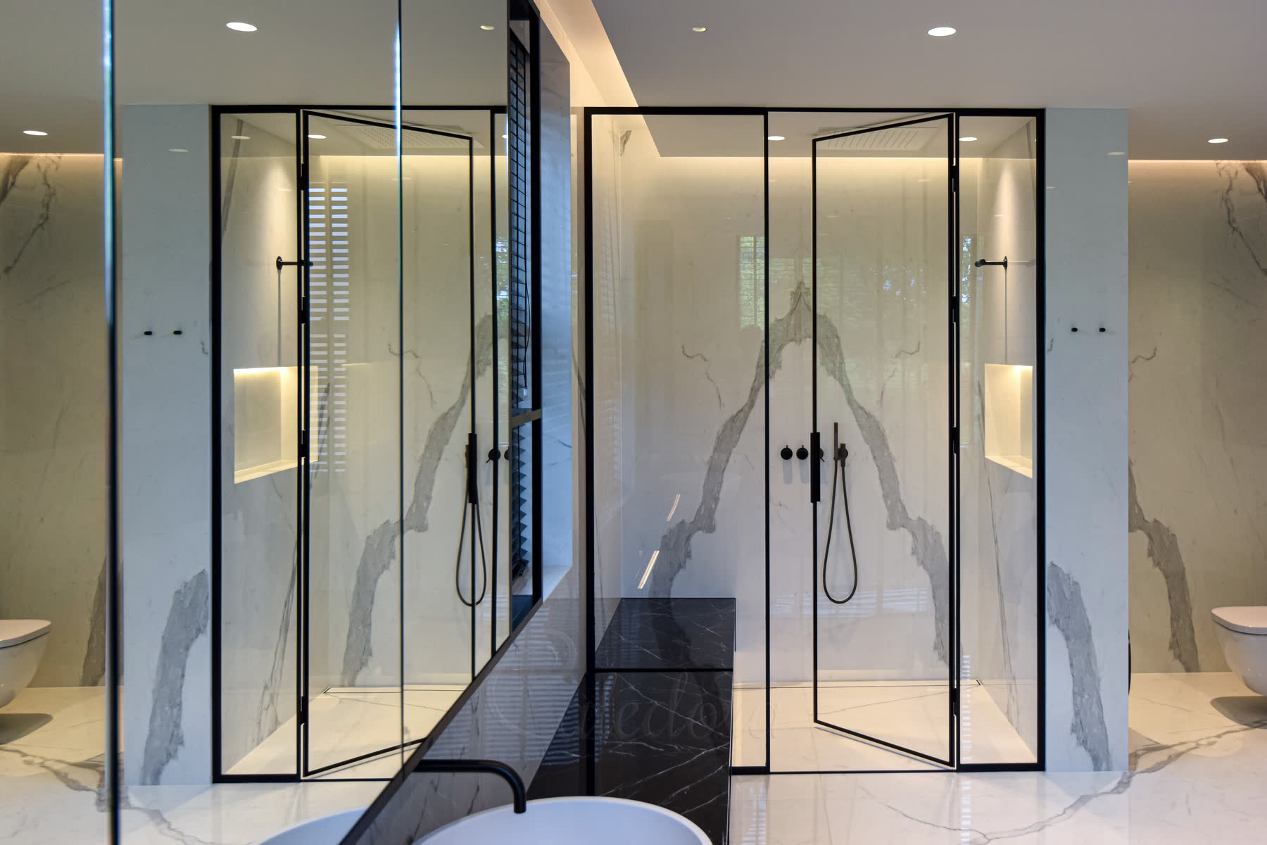 Black framed shower with rainfall shower head and bench feature