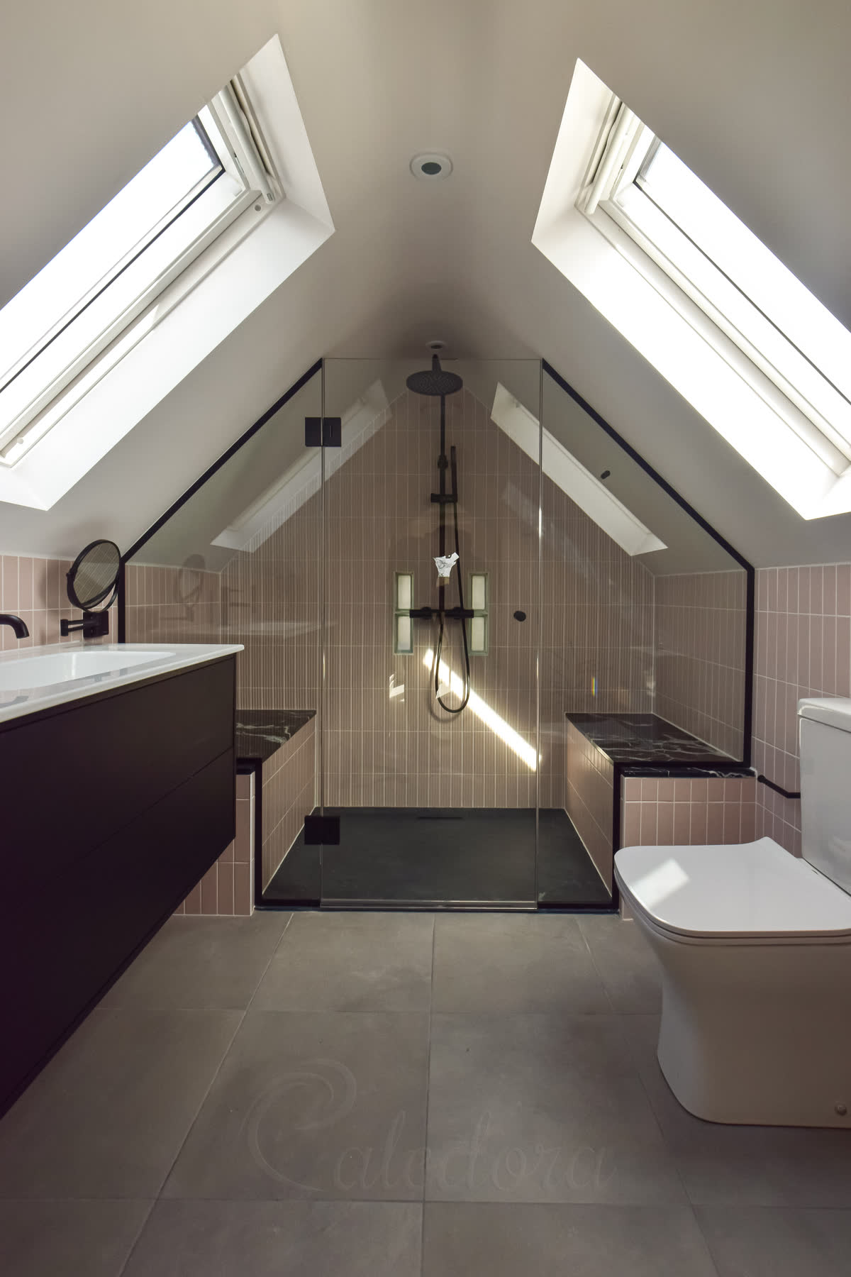 Shower enclosure glass panel notched around tiled bench with black U-channel fixings