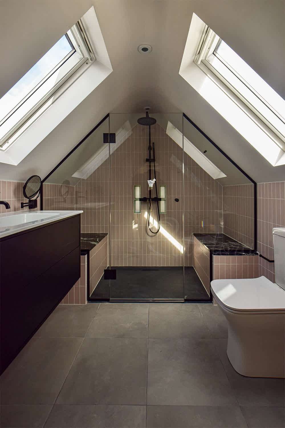 Frameless black shower enclosure under eaves with custom-shaped fixed panels and loft ceiling alignment
