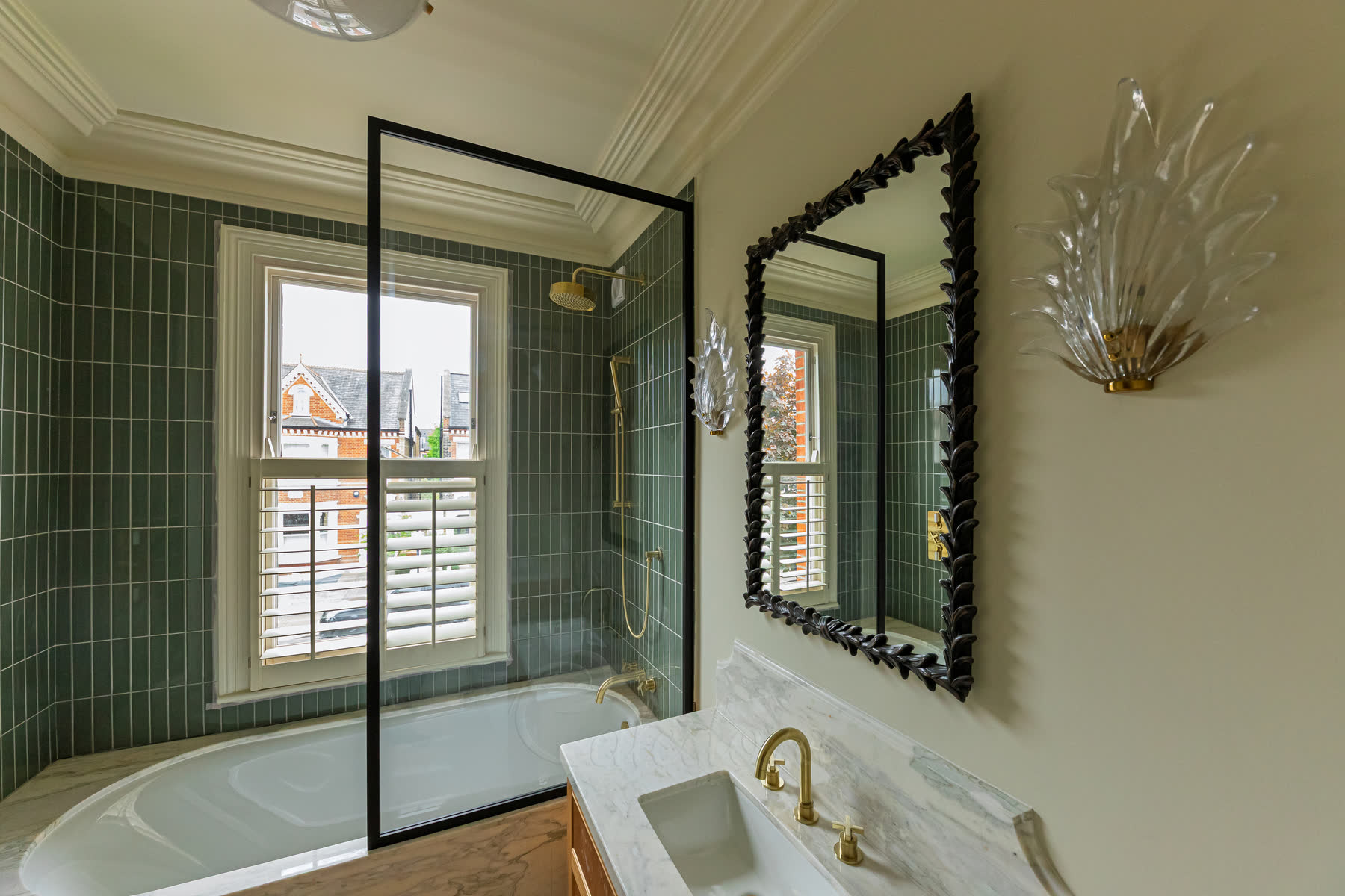 Wide angle view of black shower screen over bath with brass taps and vanity