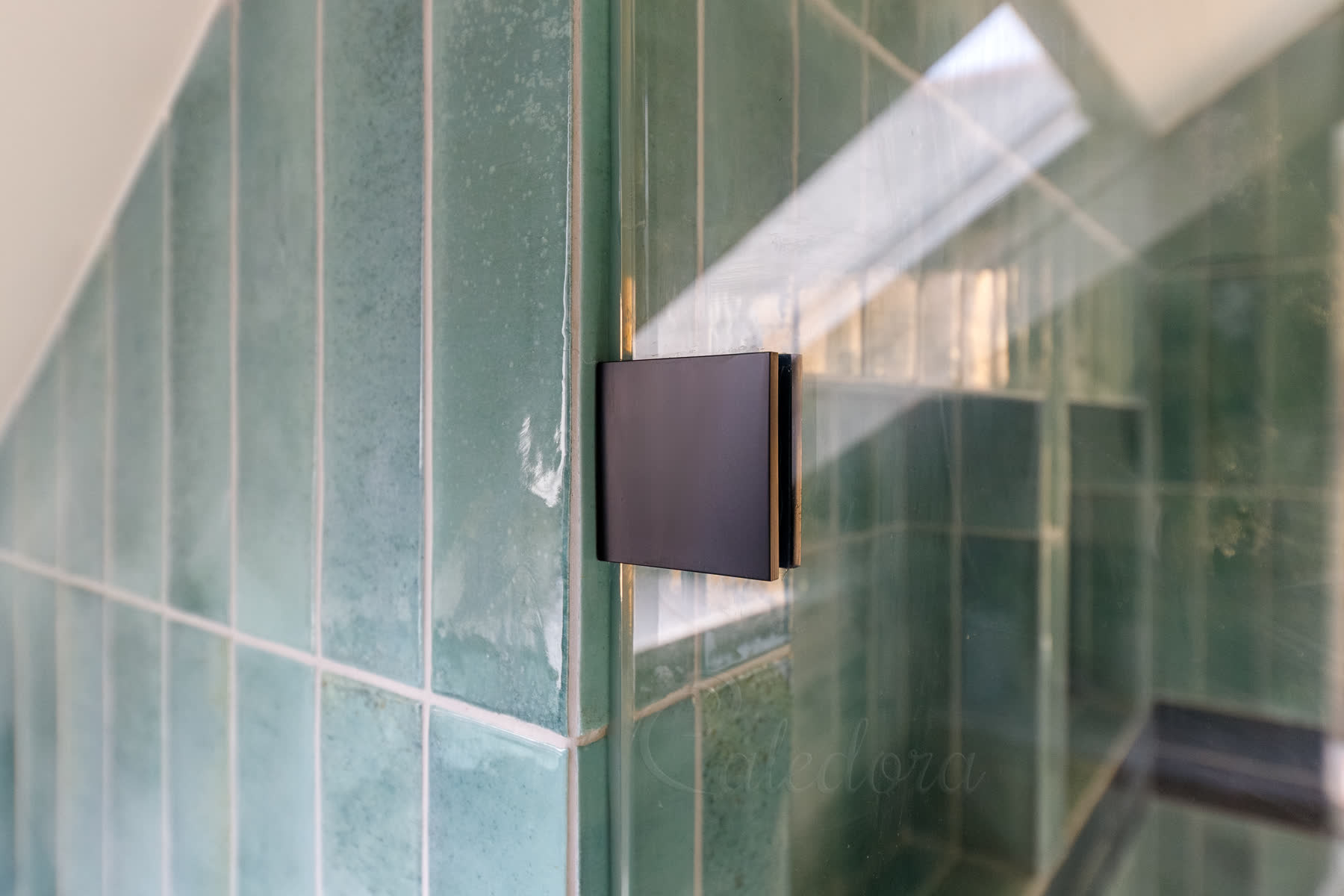 Close detail of black wall bracket supporting fixed screen with clear mastic sealing